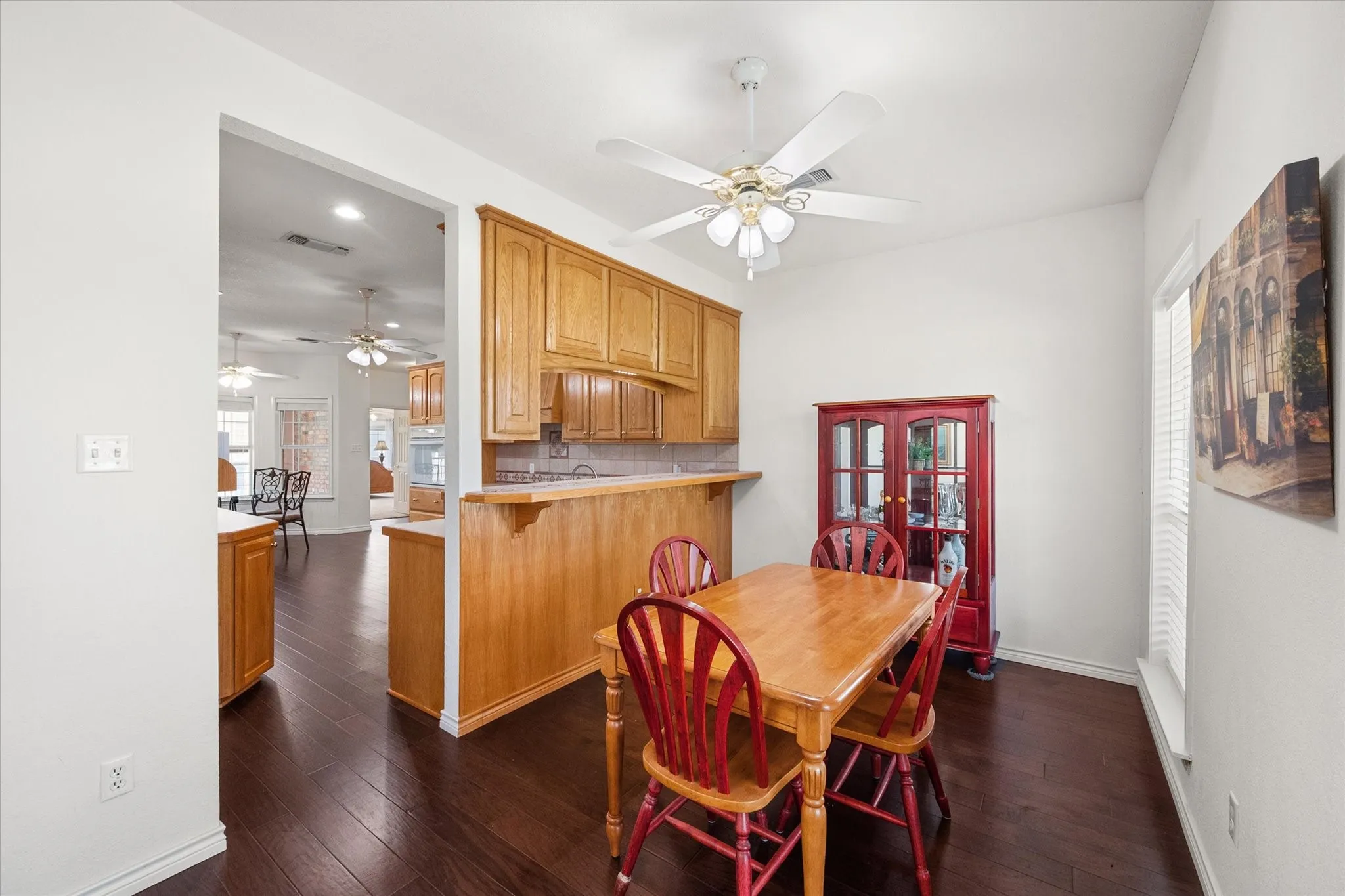 Dining area near Dallas with warm wood flooring, kitchen pass-through, and bright windows for everyday lake-area living.