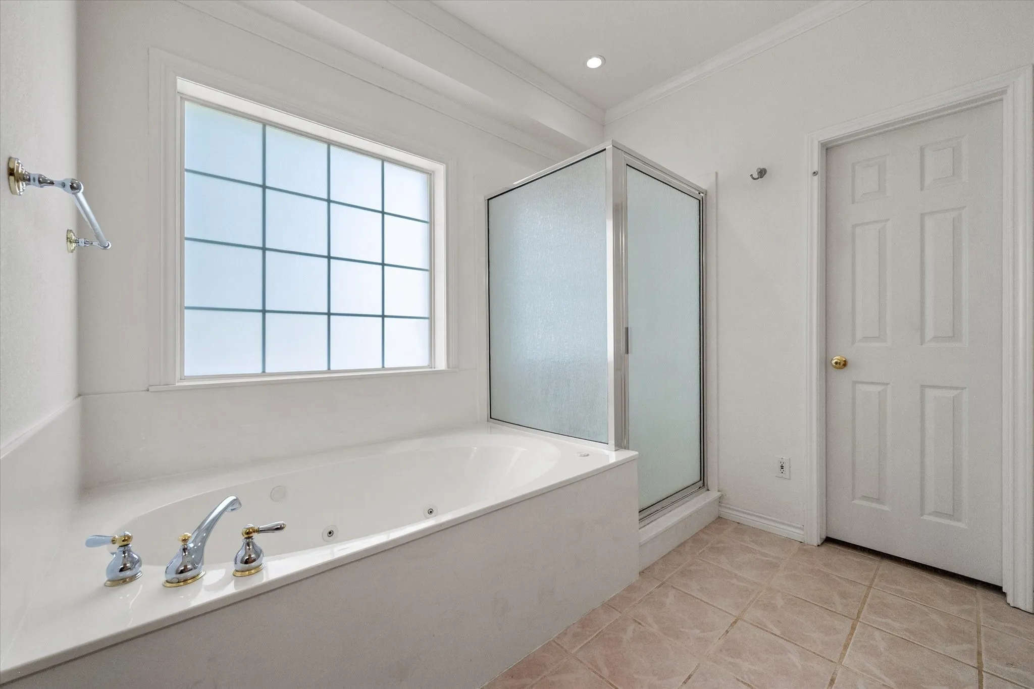 Primary bathroom near Dallas with garden tub, separate shower, and bright window for natural light.