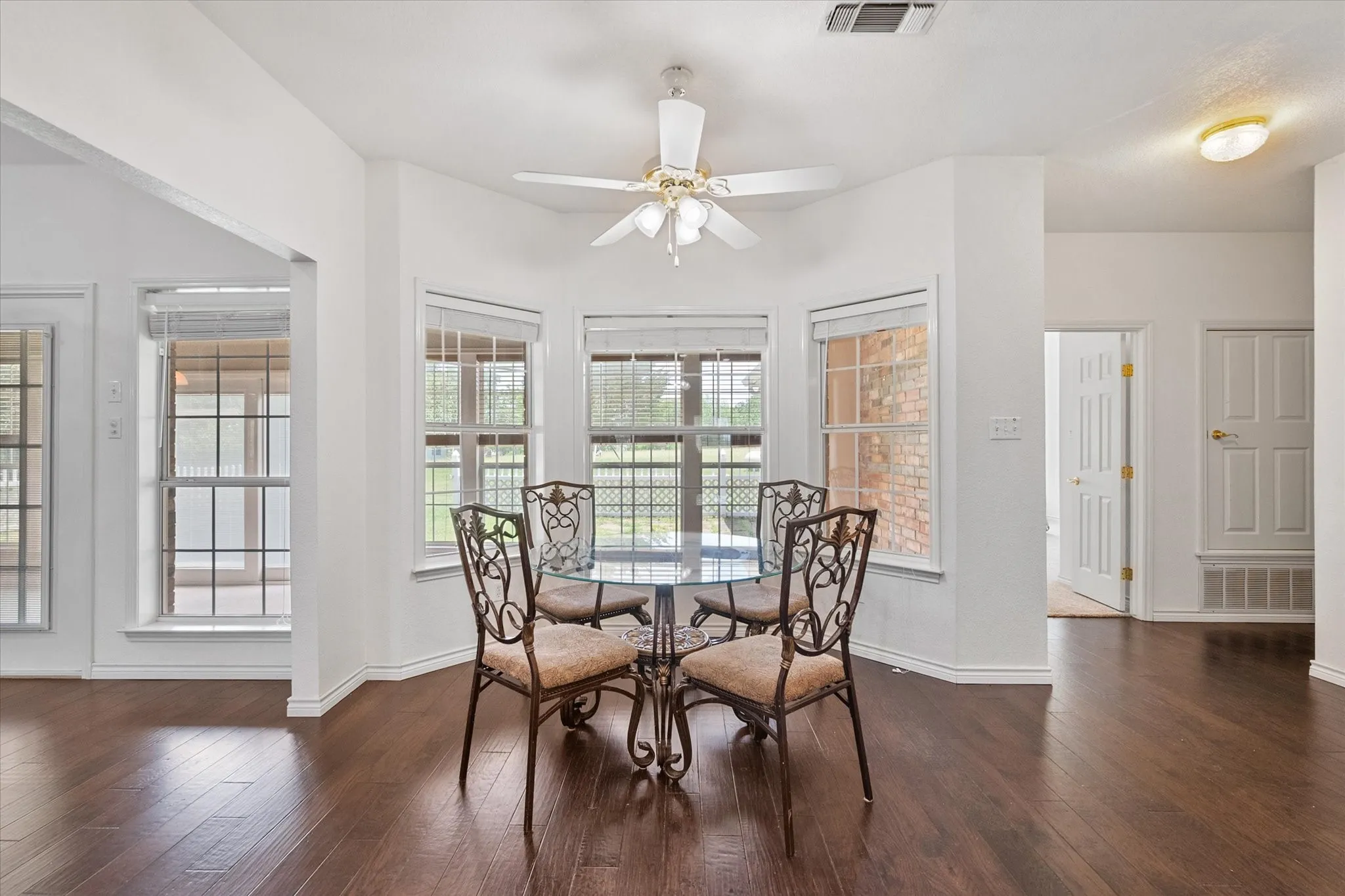 Bright breakfast nook near Corsicana surrounded by windows overlooking the fenced patio and outdoor space.