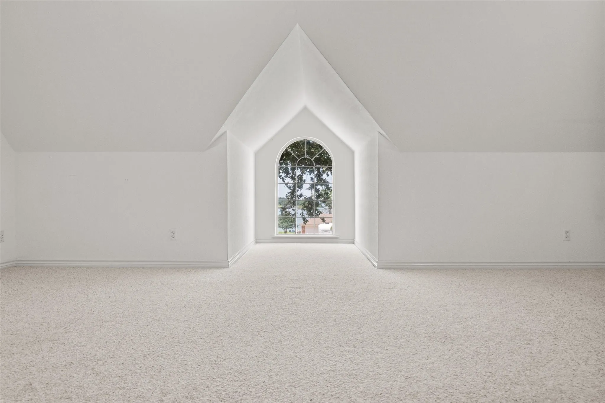 Upstairs bonus space in Streetman, TX with arched window, soft carpet, and plenty of room for multiple uses.