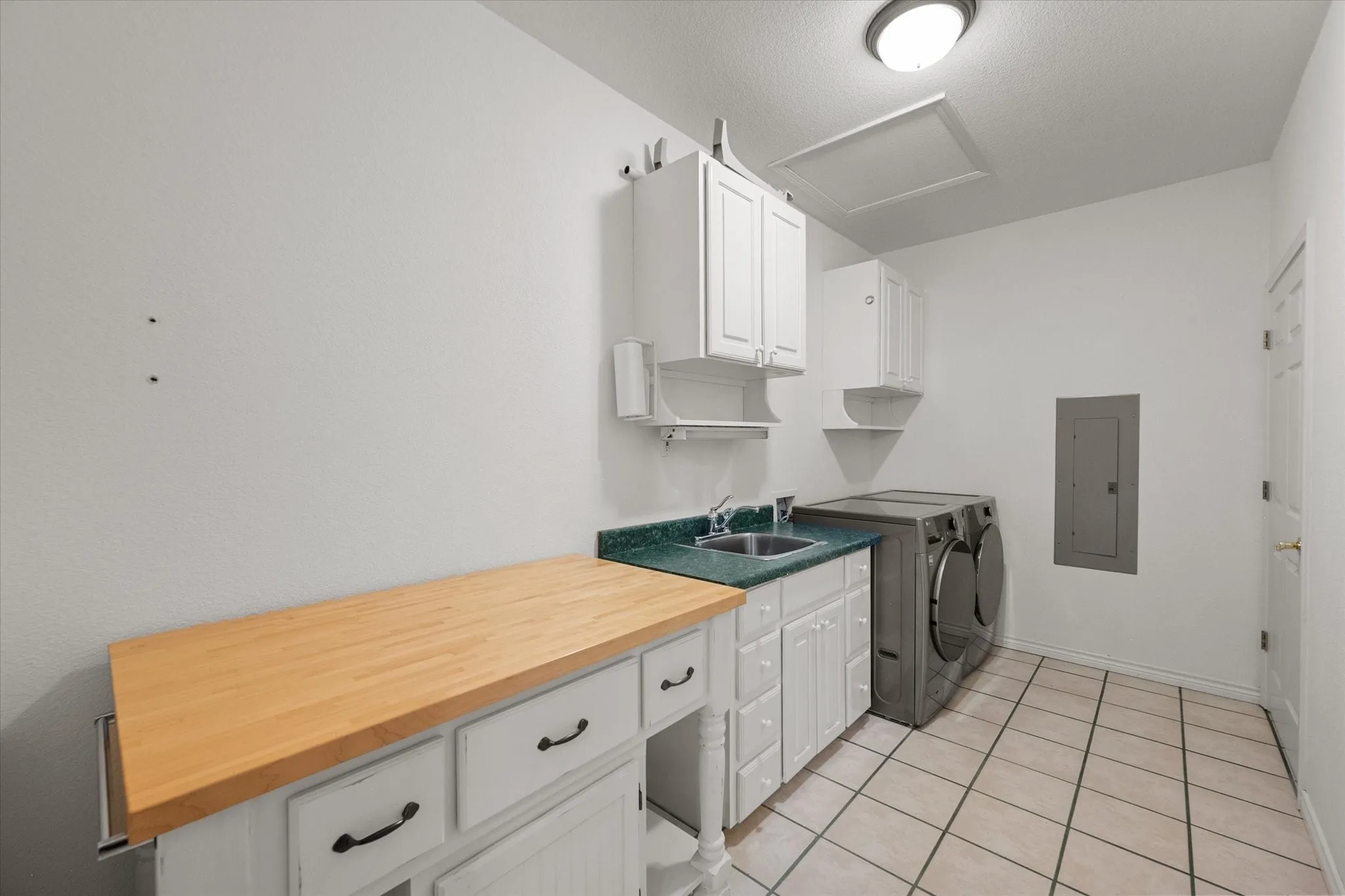 Utility room near Dallas with sink, cabinetry, washer-dryer space, and extra work surface for daily convenience.
