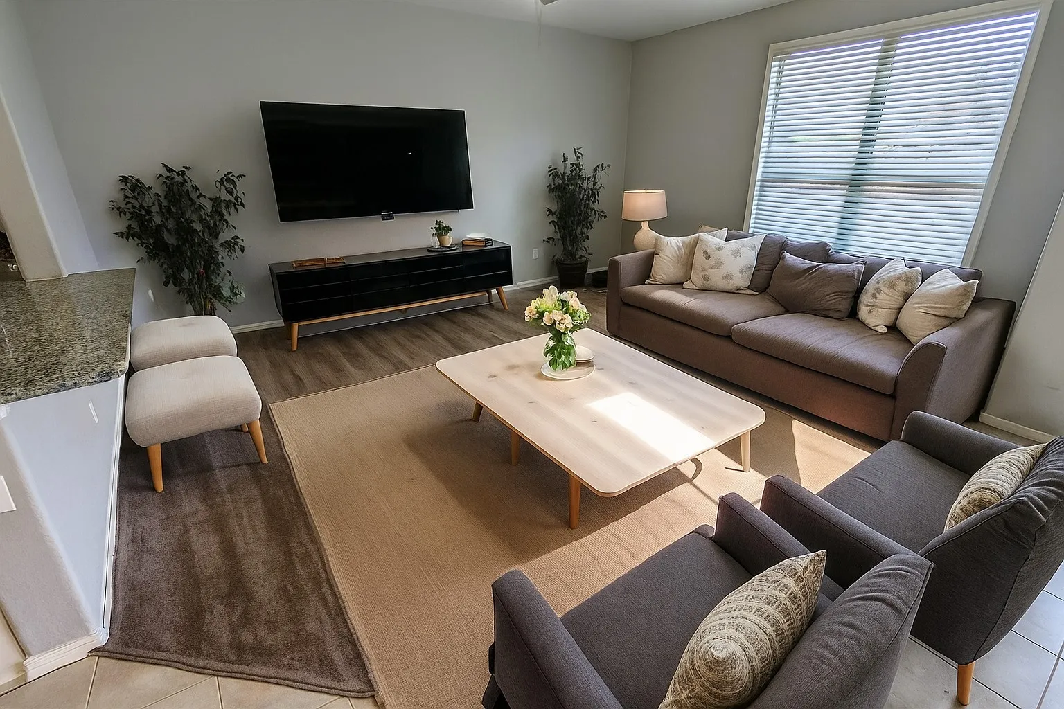 Living space featuring wood-finish flooring, a large window with blinds, and light gray wall paint