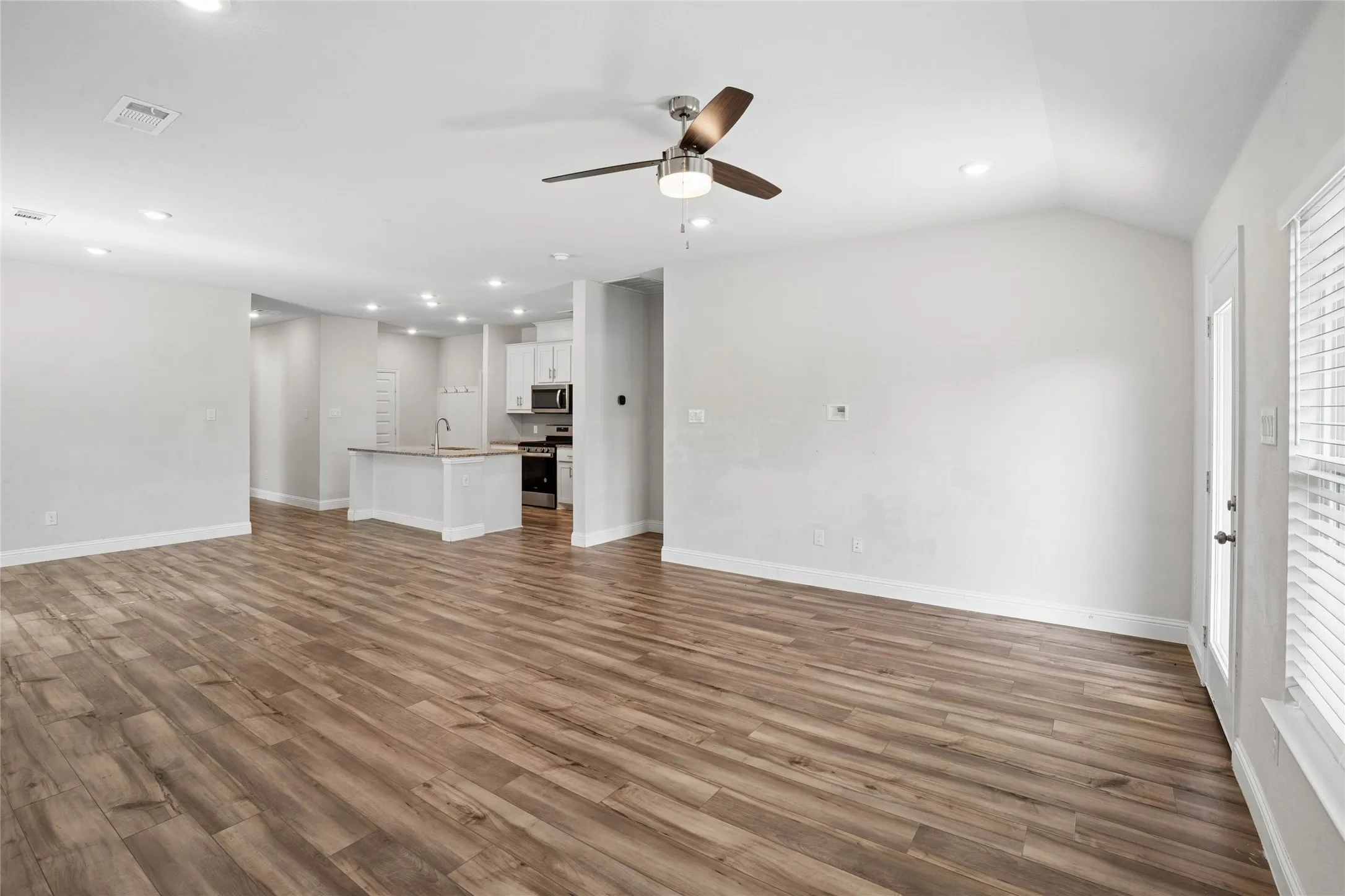 Open-concept living area featuring wood-finish flooring, recessed lighting, and a ceiling fan