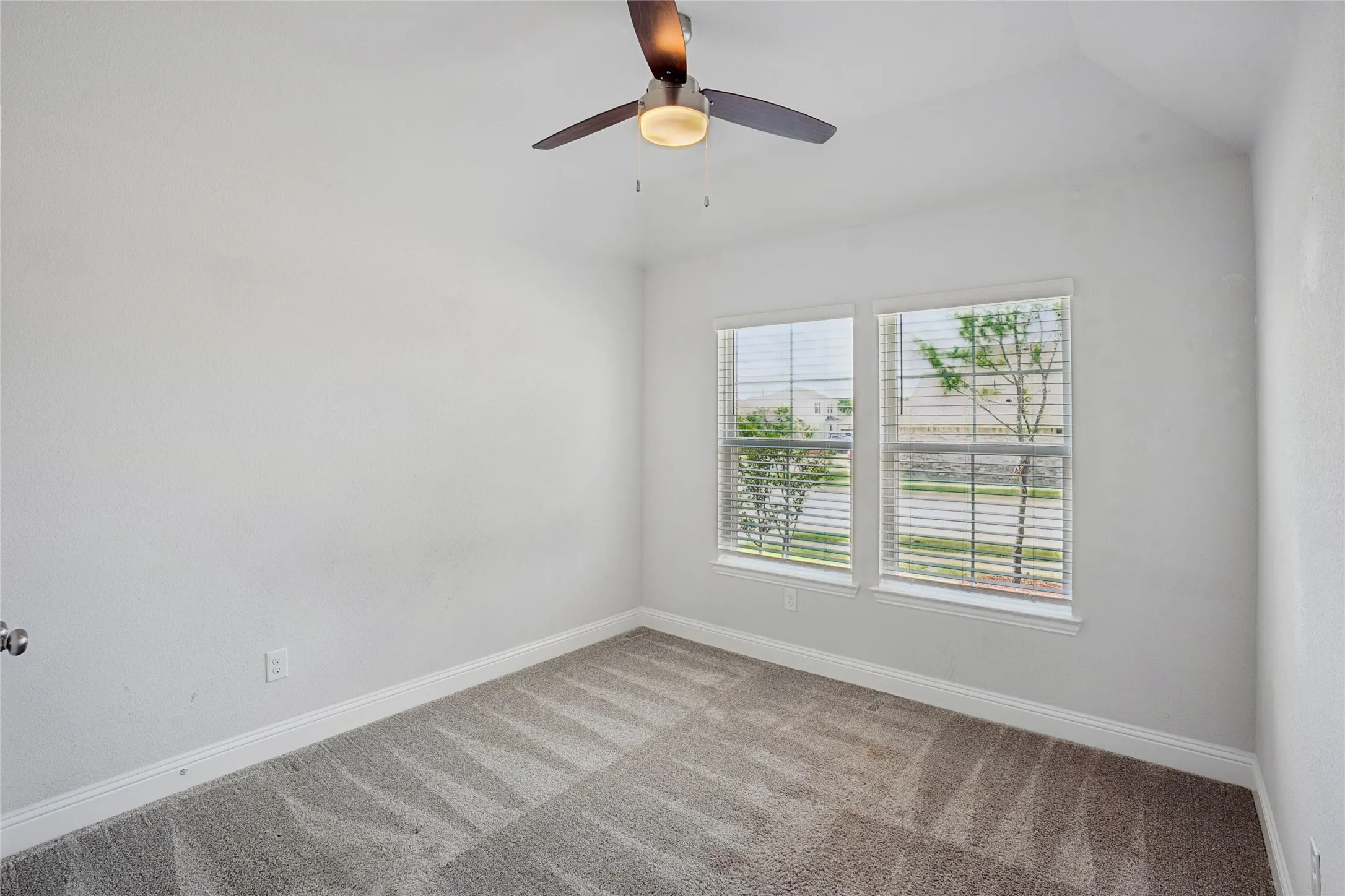 Room featuring light-toned carpeting, white walls, and a ceiling fan with integrated lighting