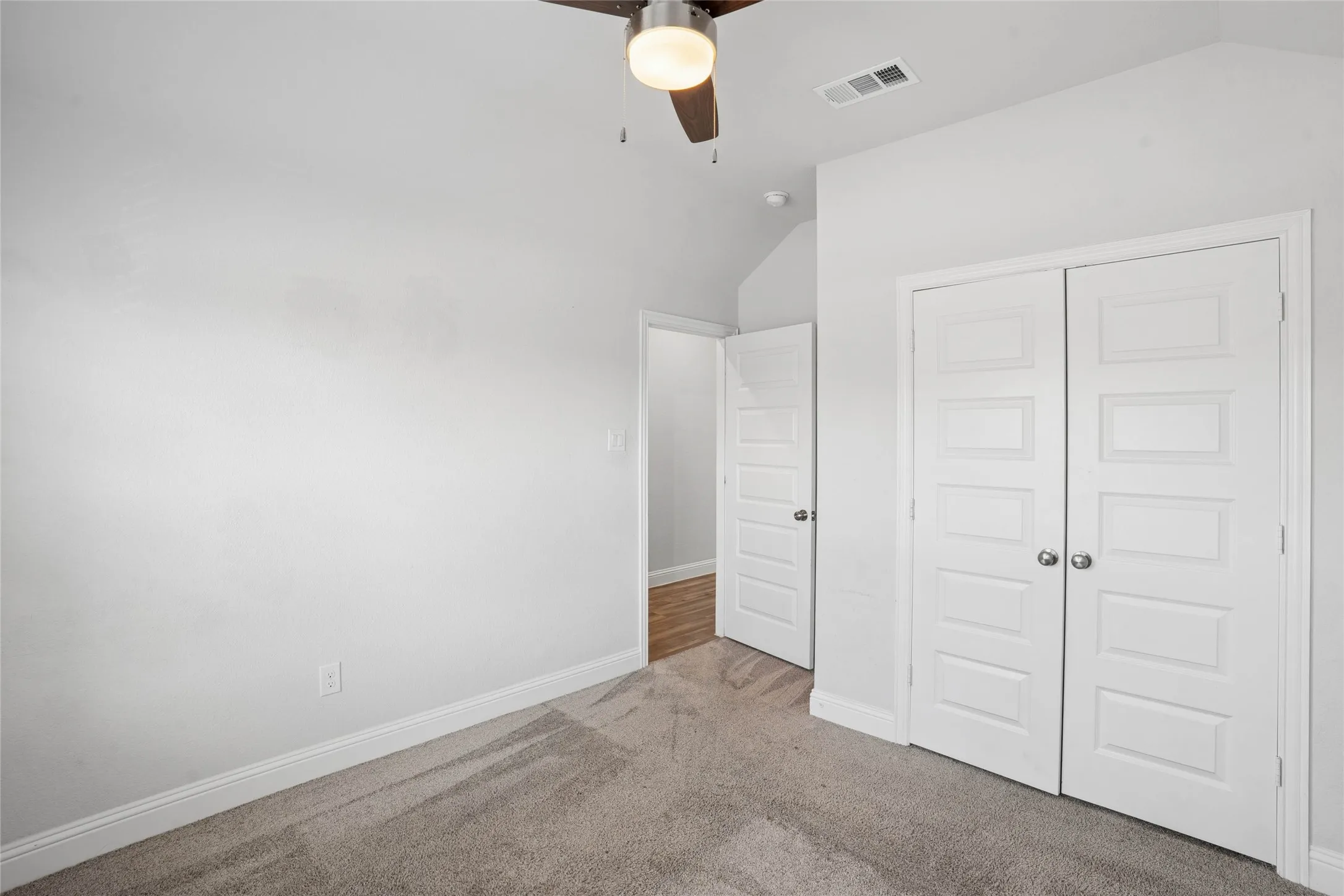Bedroom featuring neutral carpeting, white trim, a ceiling fan with integrated lighting, and a closet with bifold panel doors