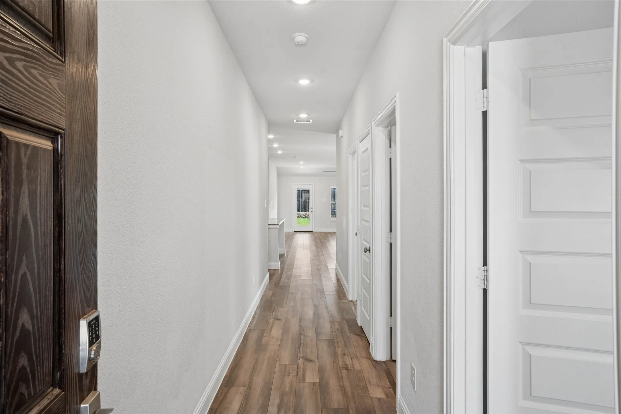Long hallway featuring wood-finish flooring and recessed lighting