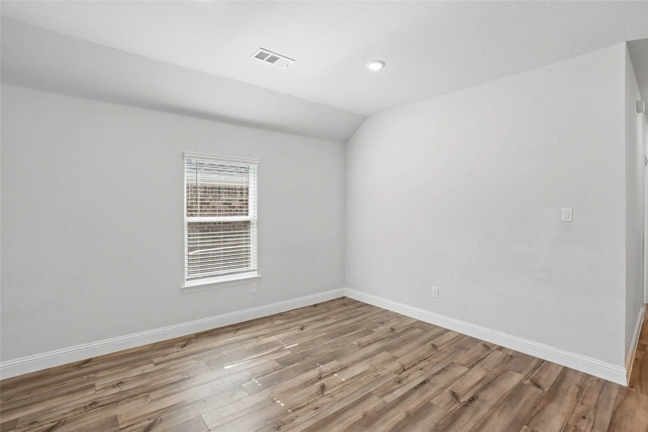 Room featuring wood-finish flooring, white baseboards, a window with blinds, recessed ceiling lighting, and light-toned walls