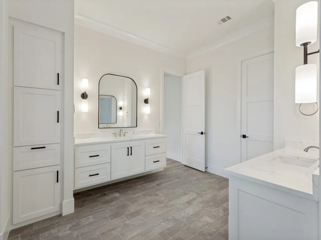 Contemporary bathroom featuring a floating double vanity with a marble-finish countertop, an arched mirror, and dual wall sconces