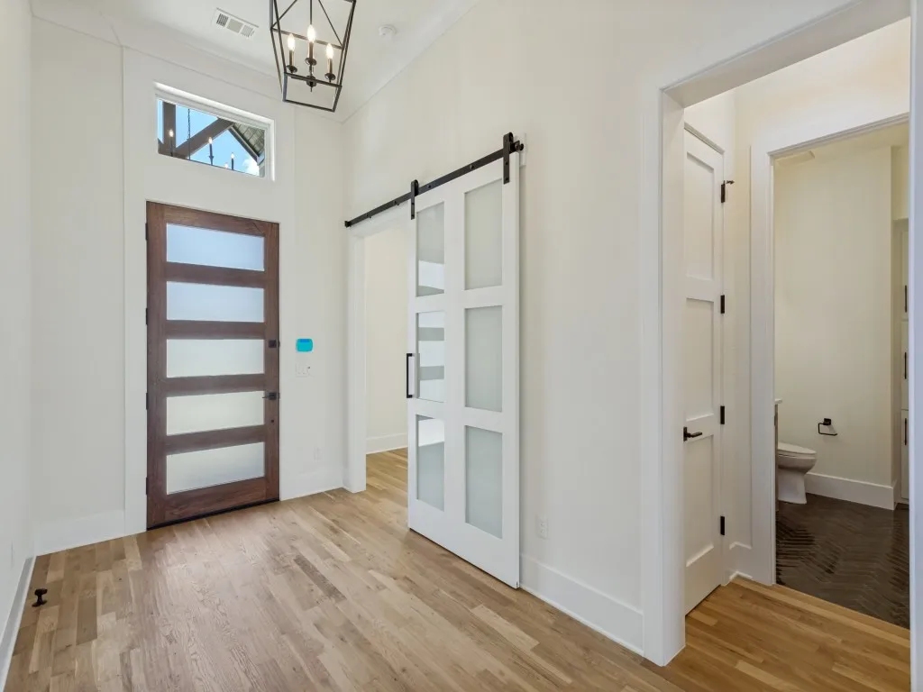 Entryway featuring wood-finish flooring, a contemporary dark wood entry door with frosted panels, and an overhead transom window