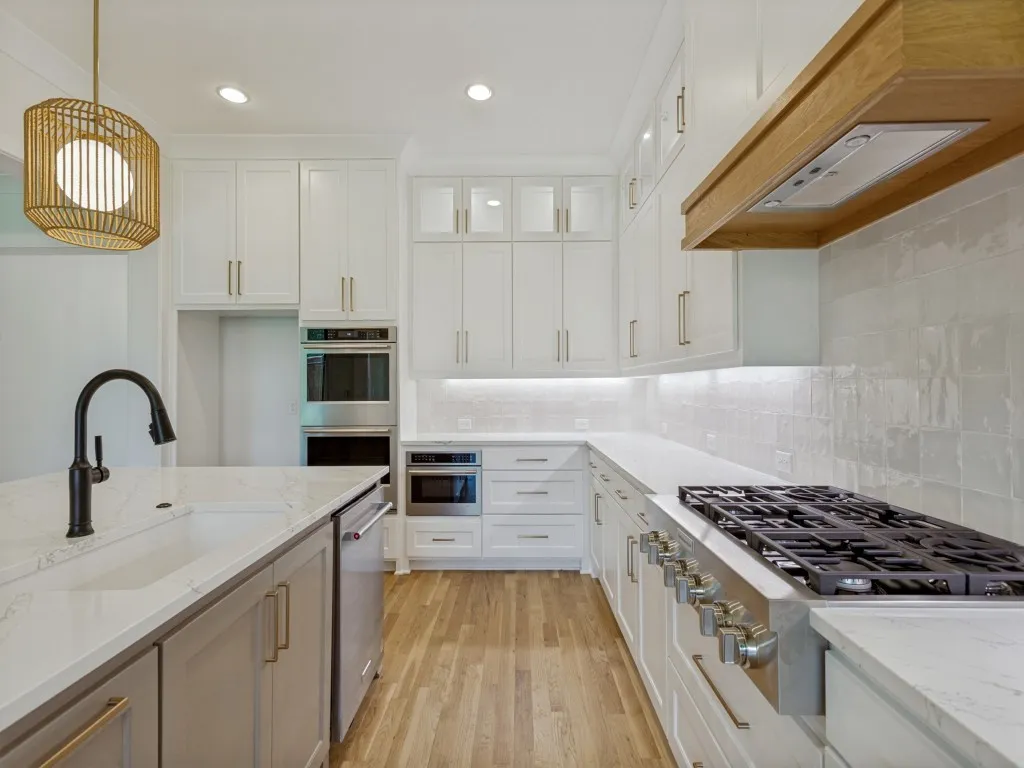 Modern kitchen featuring an integrated gas range, stainless steel appliances, and wood-finish flooring