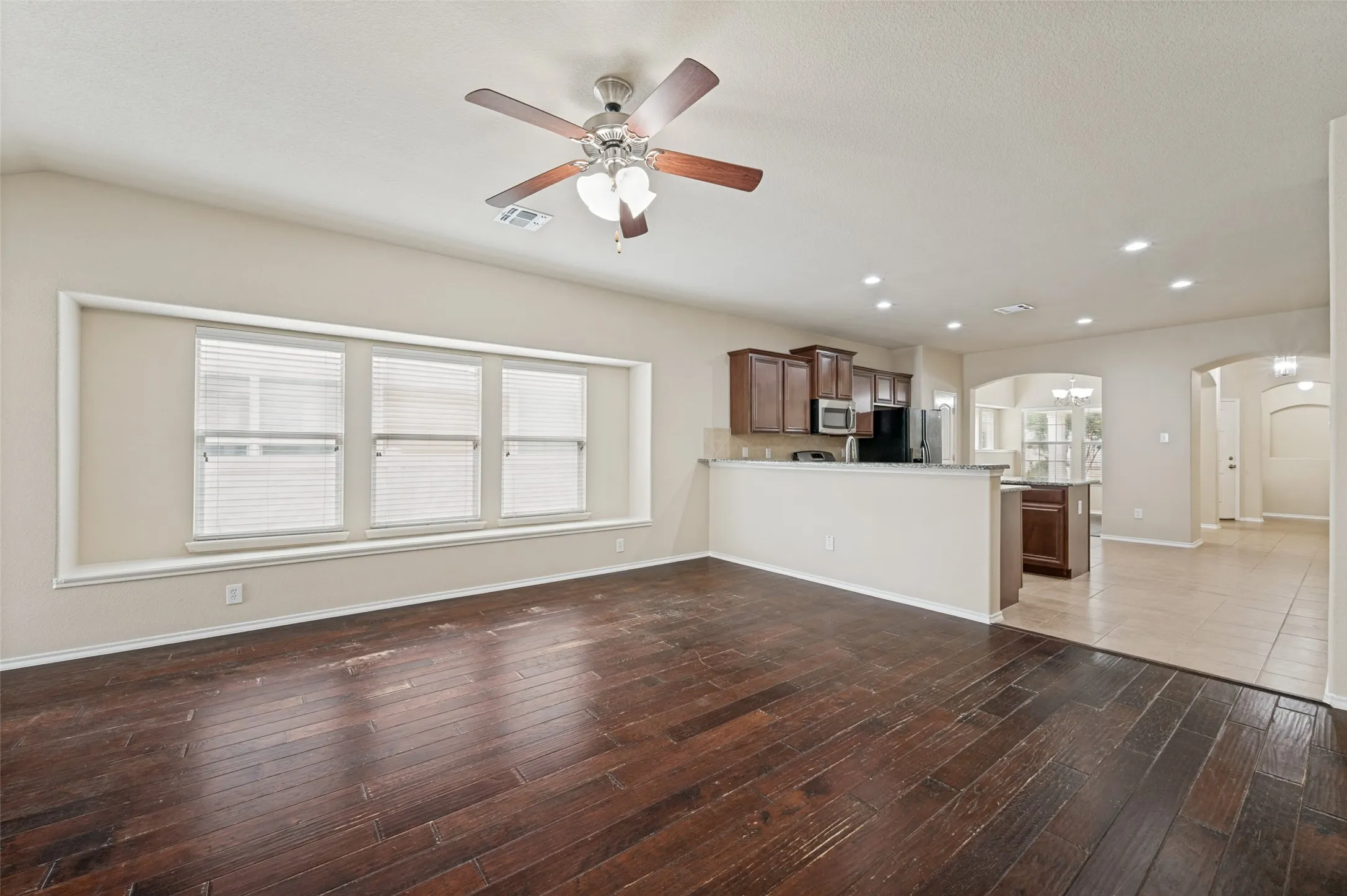Expansive living area featuring rich wood-finish flooring and a ceiling fan