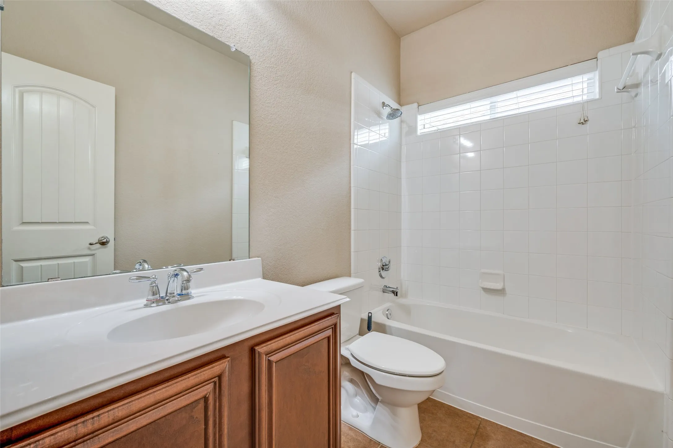 Vanity with a white countertop and integrated sink, chrome faucet, and wood-finish cabinetry