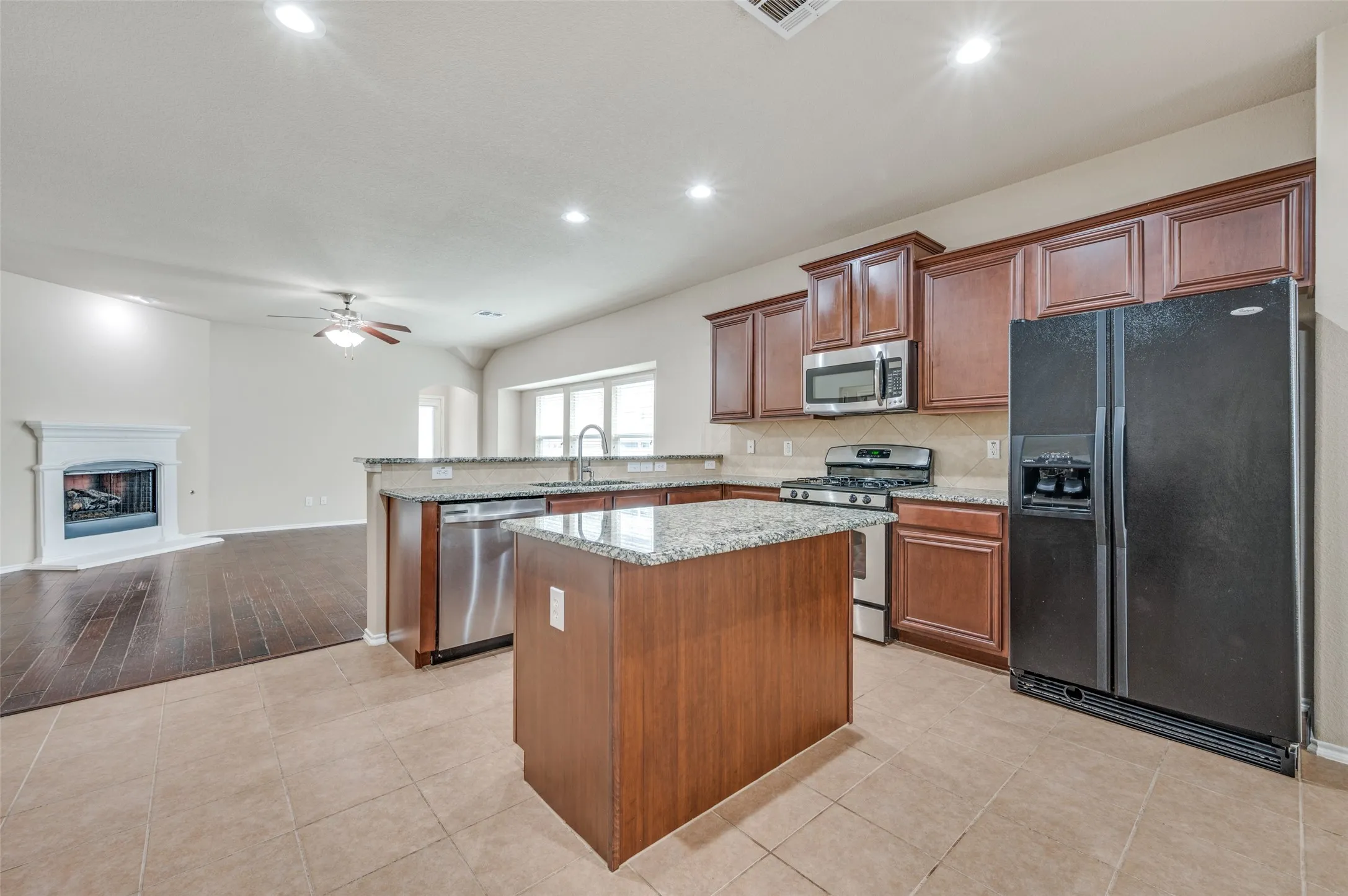 Kitchen featuring wood-finish cabinetry, a central island with a stone countertop, and stainless steel appliances