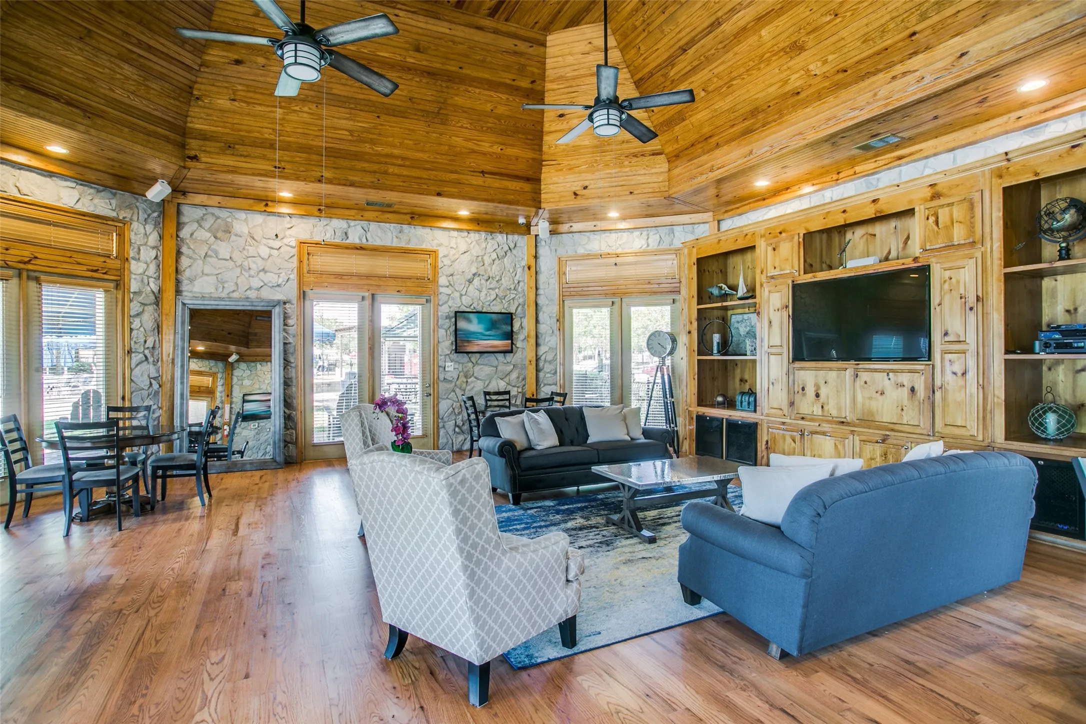 Expansive living area featuring a vaulted wood-paneled ceiling with recessed lighting and ceiling fans