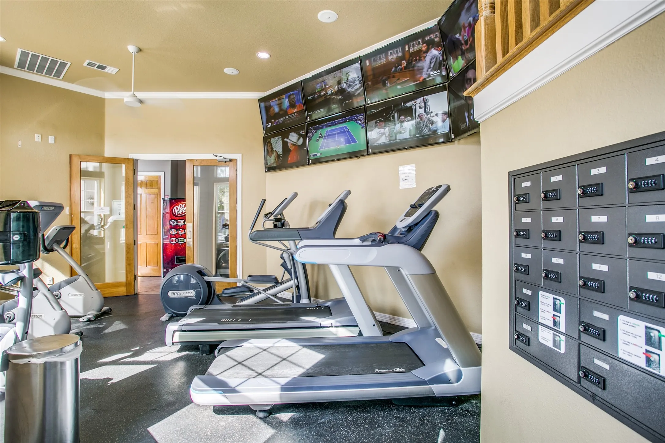 Fitness center featuring cardio equipment, multiple wall-mounted televisions, and durable rubber flooring