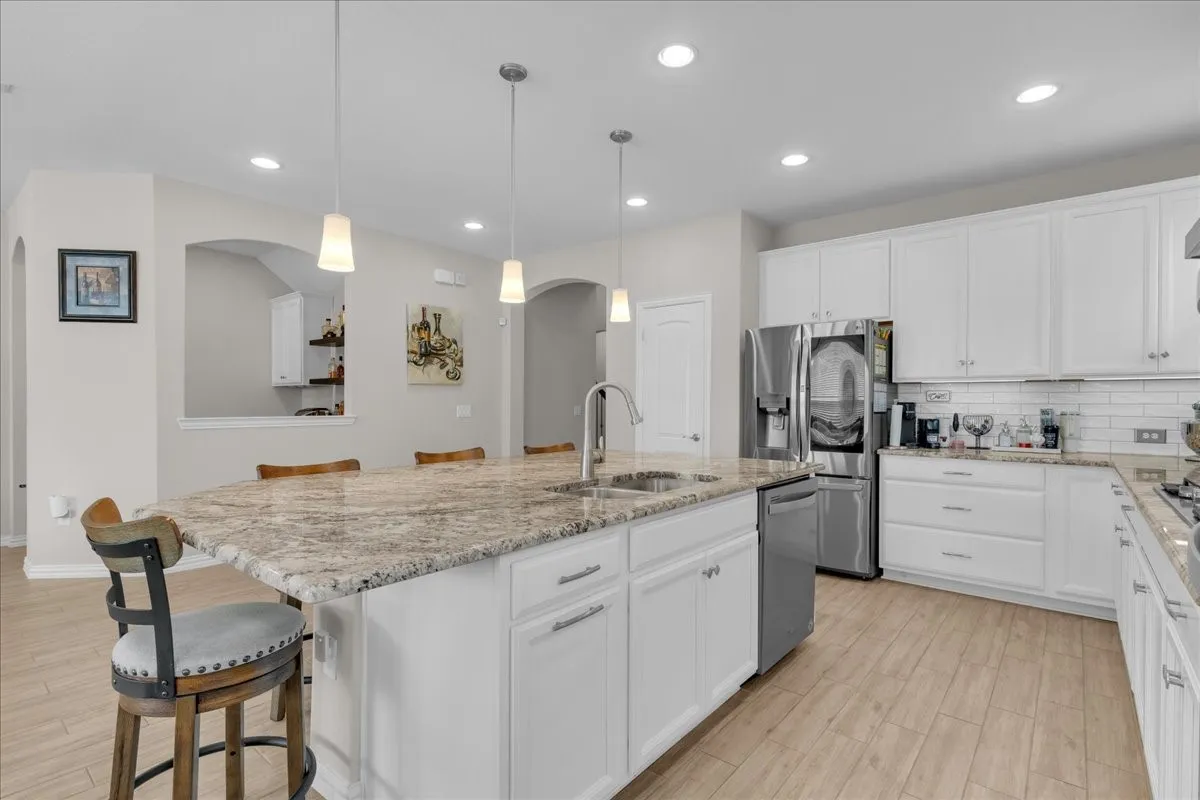 Kitchen featuring an expansive island with a stone countertop, an undermount sink, and pendant lighting