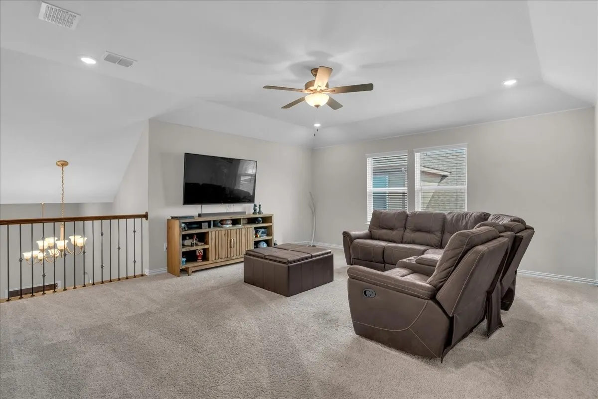 Carpeted secondary living space featuring a vaulted ceiling with recessed lighting and a ceiling fan