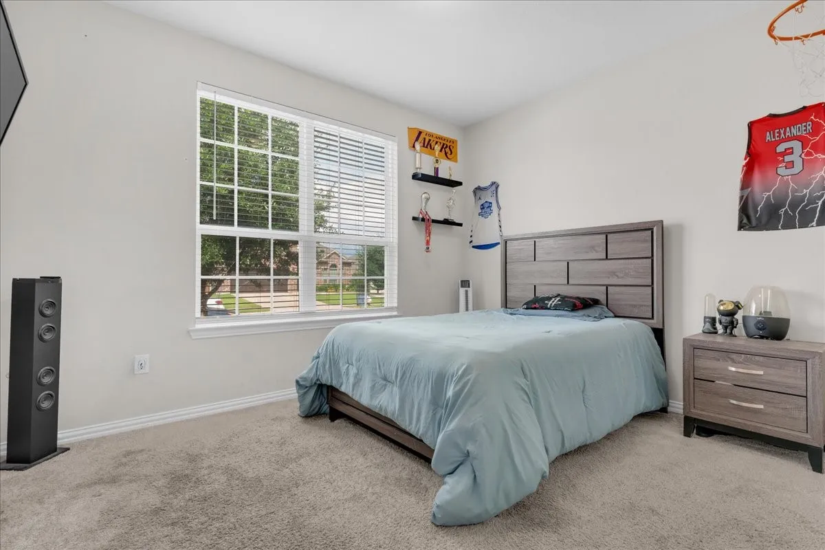 Carpeted room featuring a large window with horizontal blinds, providing natural light and exterior views