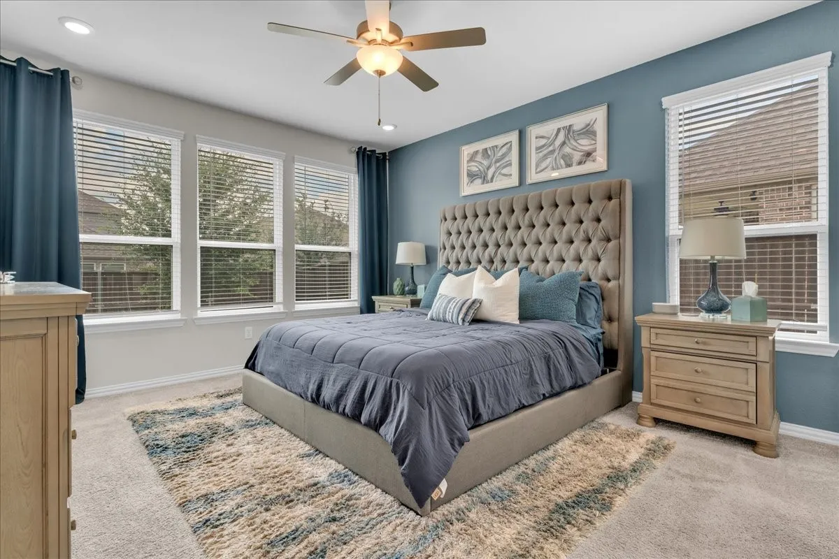 Carpeted room featuring a ceiling fan with integrated lighting, recessed lighting, and multiple windows with blinds