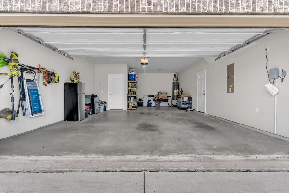 Attached garage featuring a concrete floor, light-colored walls, and a visible electrical panel