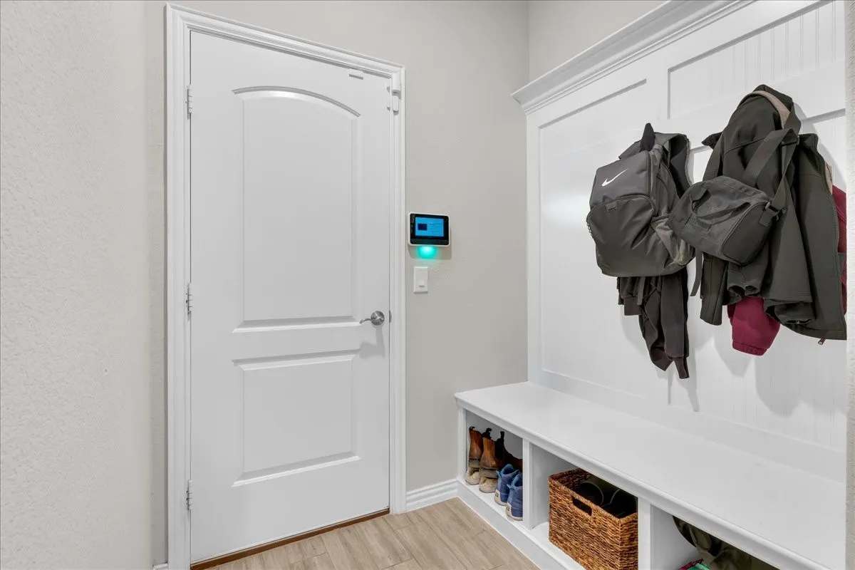 Built-in mudroom bench with cubby storage, white beadboard accent wall, and coat hooks