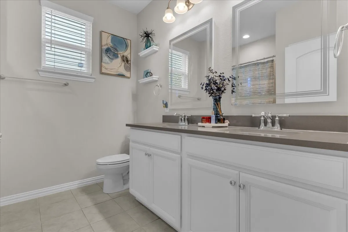 Double vanity with white cabinetry, integrated sinks, and a stone-finish countertop