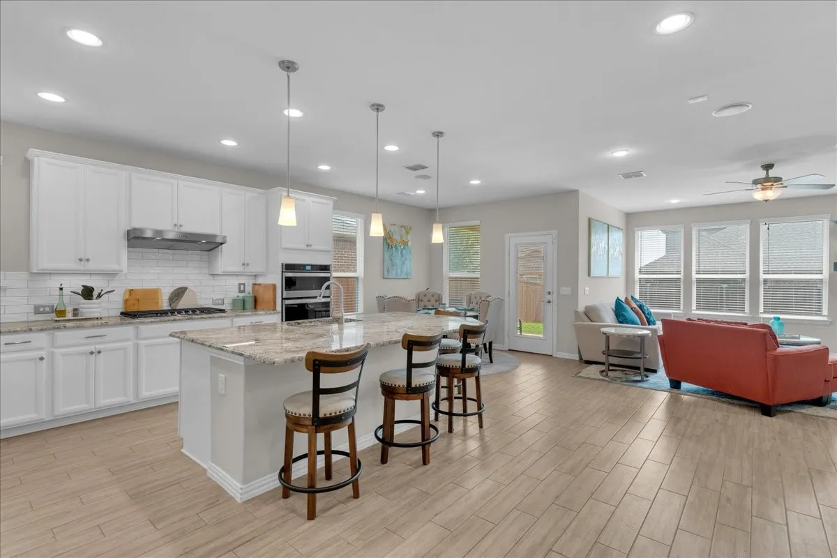 Kitchen featuring white cabinetry, subway tile backsplash, granite countertops, and built-in double ovens