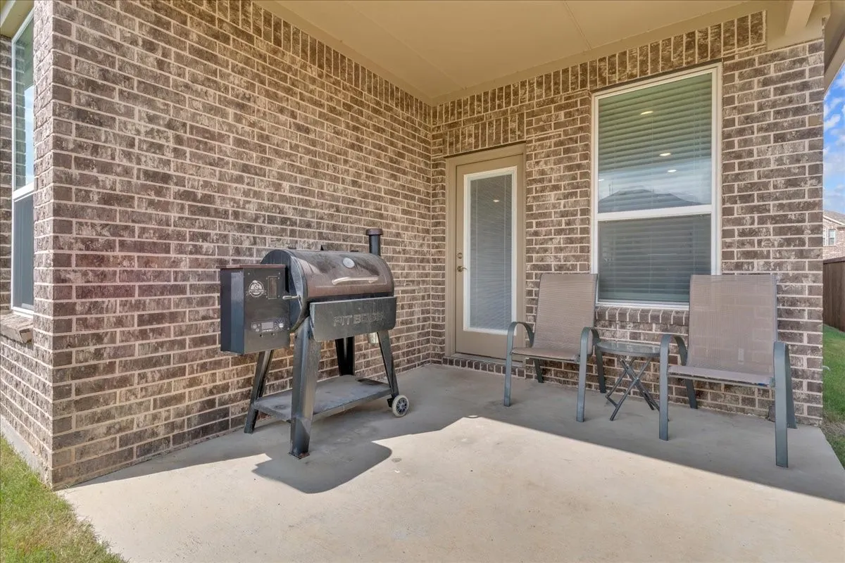 Covered concrete patio featuring a brick exterior wall