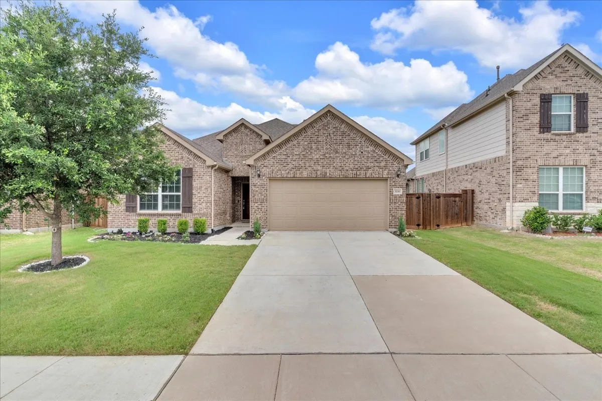 Brick exterior featuring decorative shutters, a two-car garage, and a concrete driveway