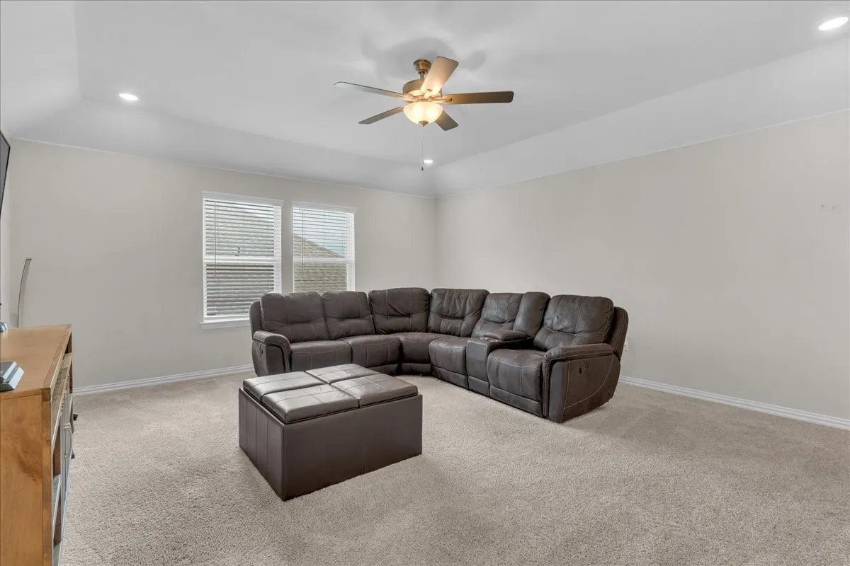 Spacious room featuring neutral carpet flooring, recessed lighting, a ceiling fan, and large windows with blinds