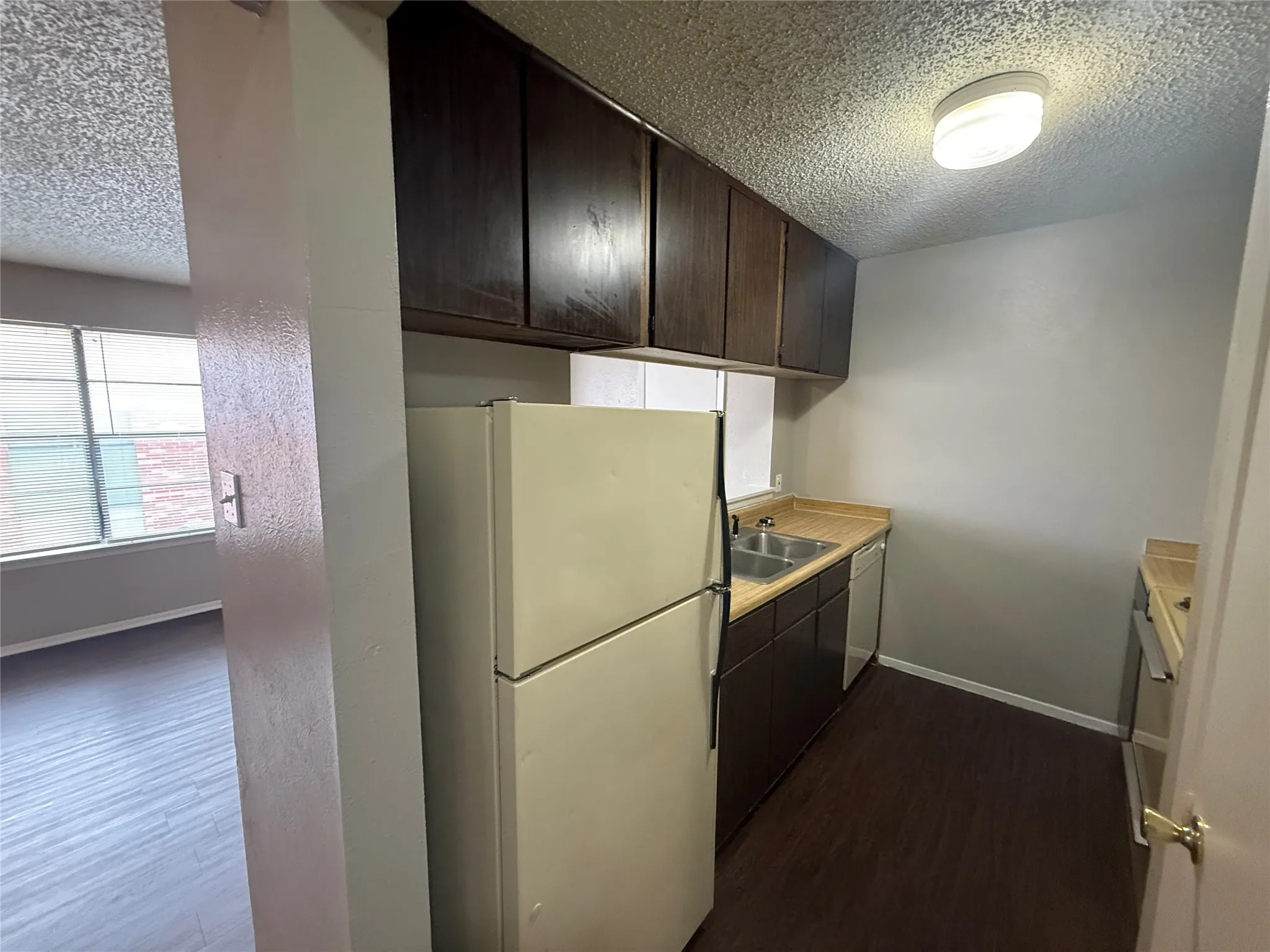 Galley kitchen featuring wood-finish flooring, dark cabinetry, and light-toned countertops