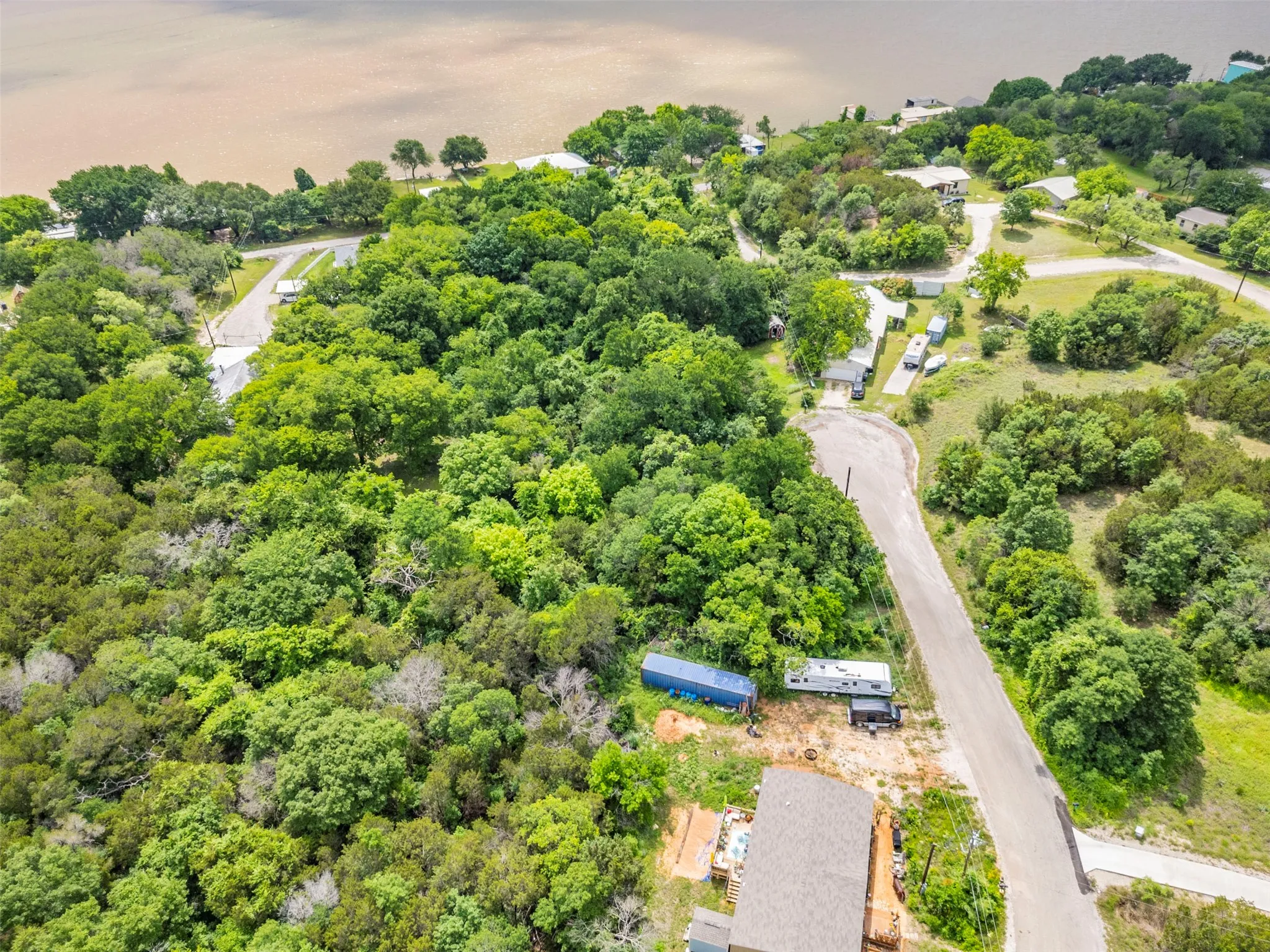Expansive wooded land parcel featuring a visible roadway and proximity to a body of water