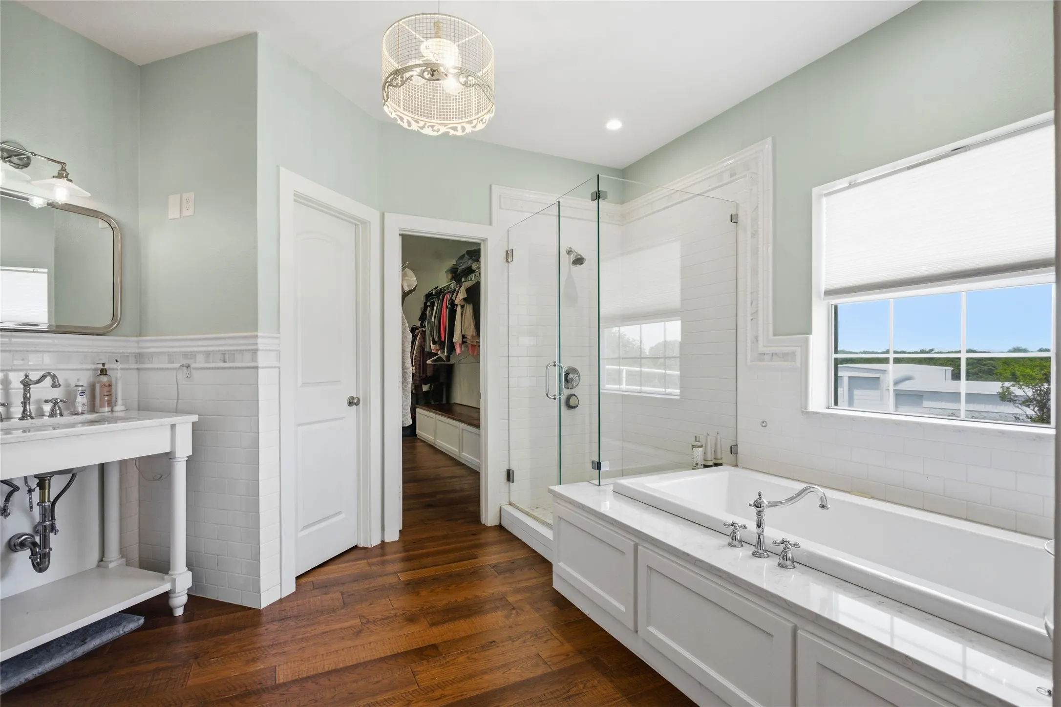 The primary bath features a large square soaking tub with views to the yard, as well as a fun farm-style vanity and large glass shower  You can access the closet area through the open door.