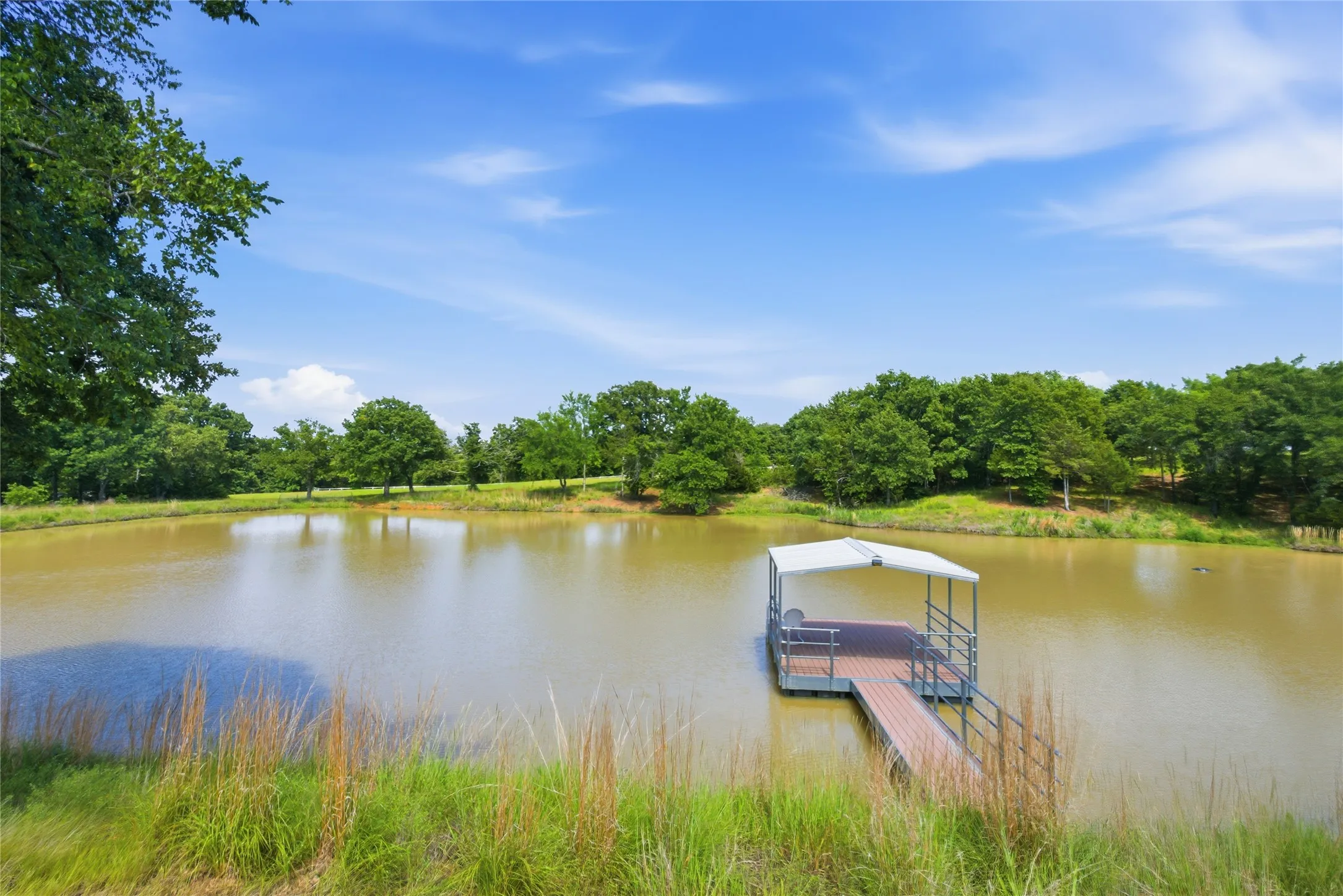 An extensive pond with a covered dock with trees all around it invites you to spend some time relaxing.