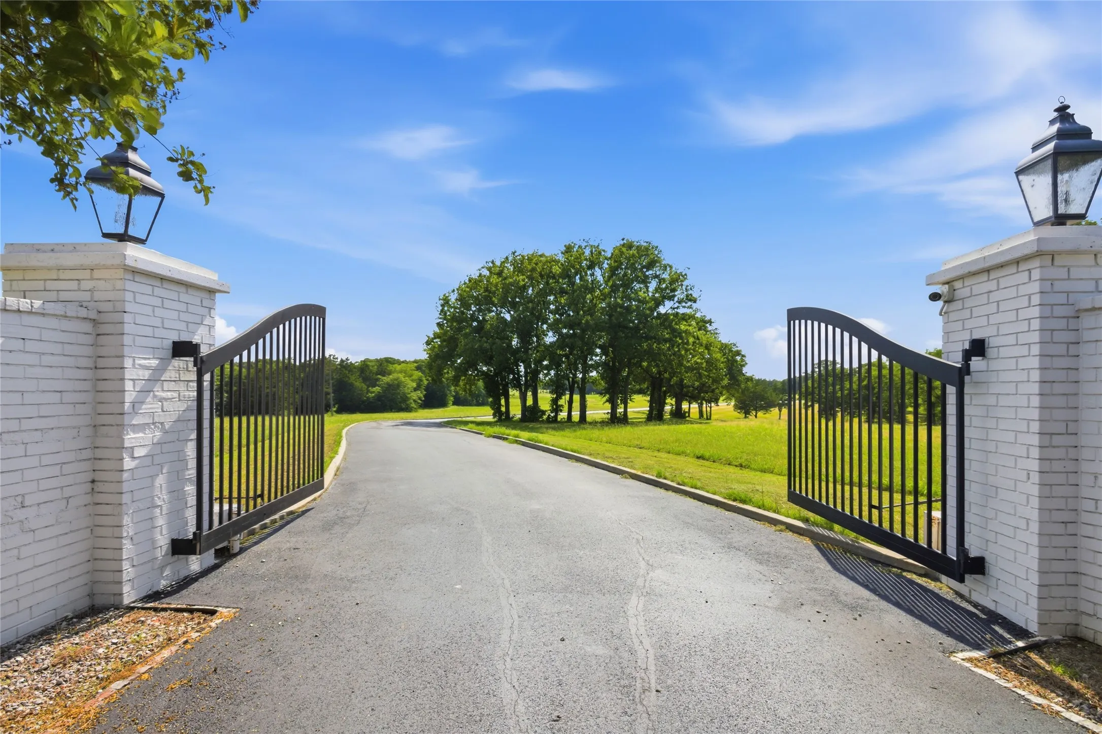 Welcome!  A brick entry with a remote control gate leads you on a paved road with curbs into this property.