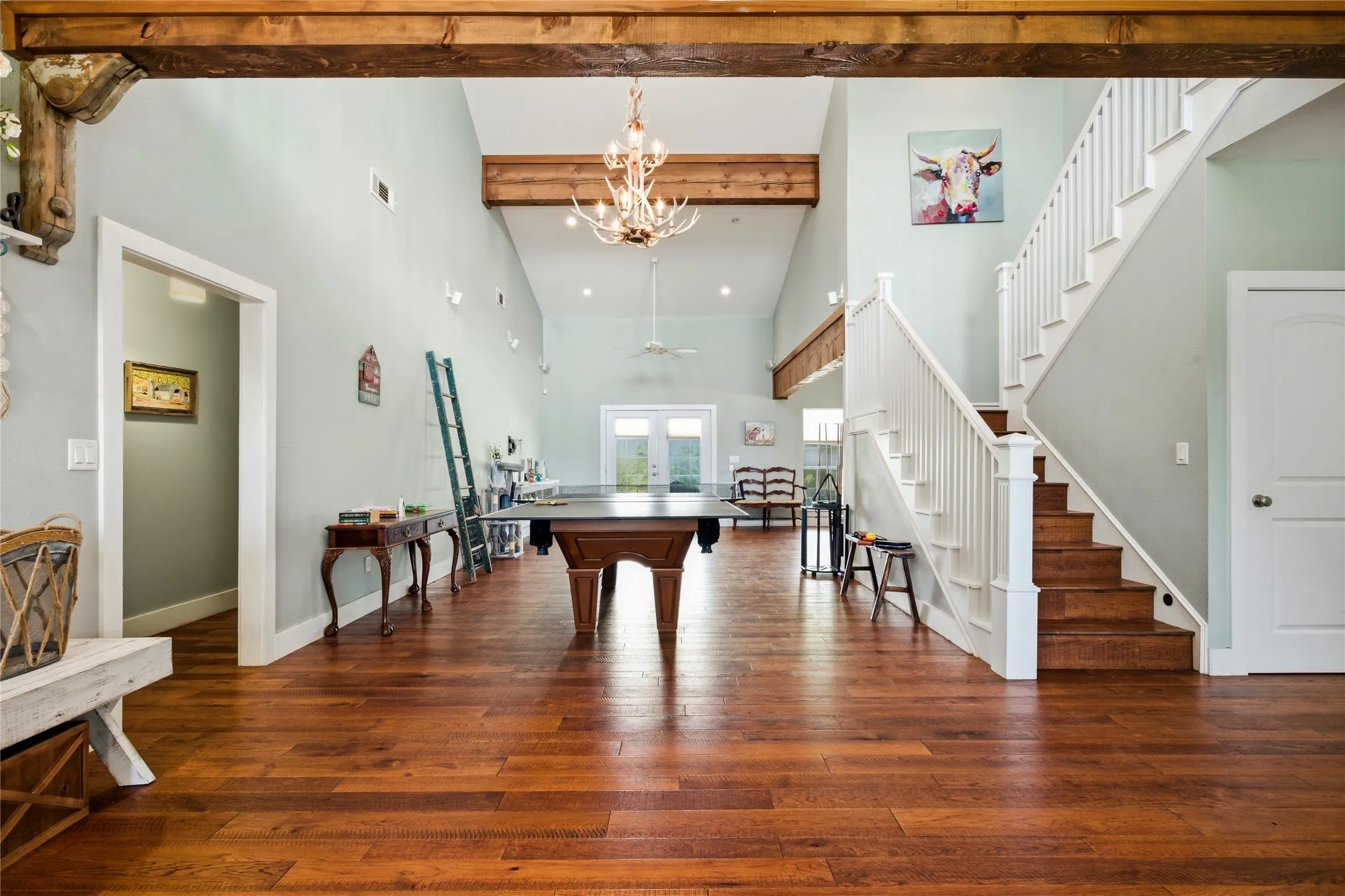 Walk into a grand room that stretches 40+ feet to the back door.  Gorgeous beams immediately catch your eye and draw you to the high ceiling in this room.  Living areas at both ends with a game area in between welcome you home.  The primary suite is the left with staircase leading upstairs on the right.  There is also another main floor bedroom to the right on this floor.