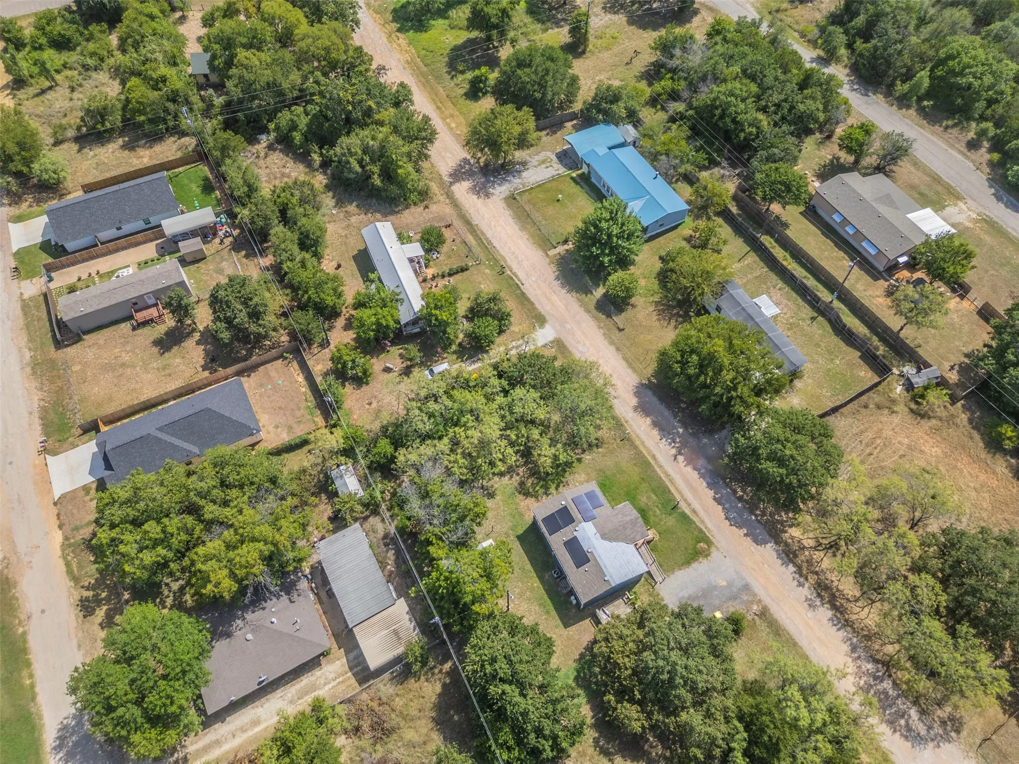 Aerial perspective showcasing multiple properties situated on a substantial lot, featuring a mix of mature trees and open spaces
