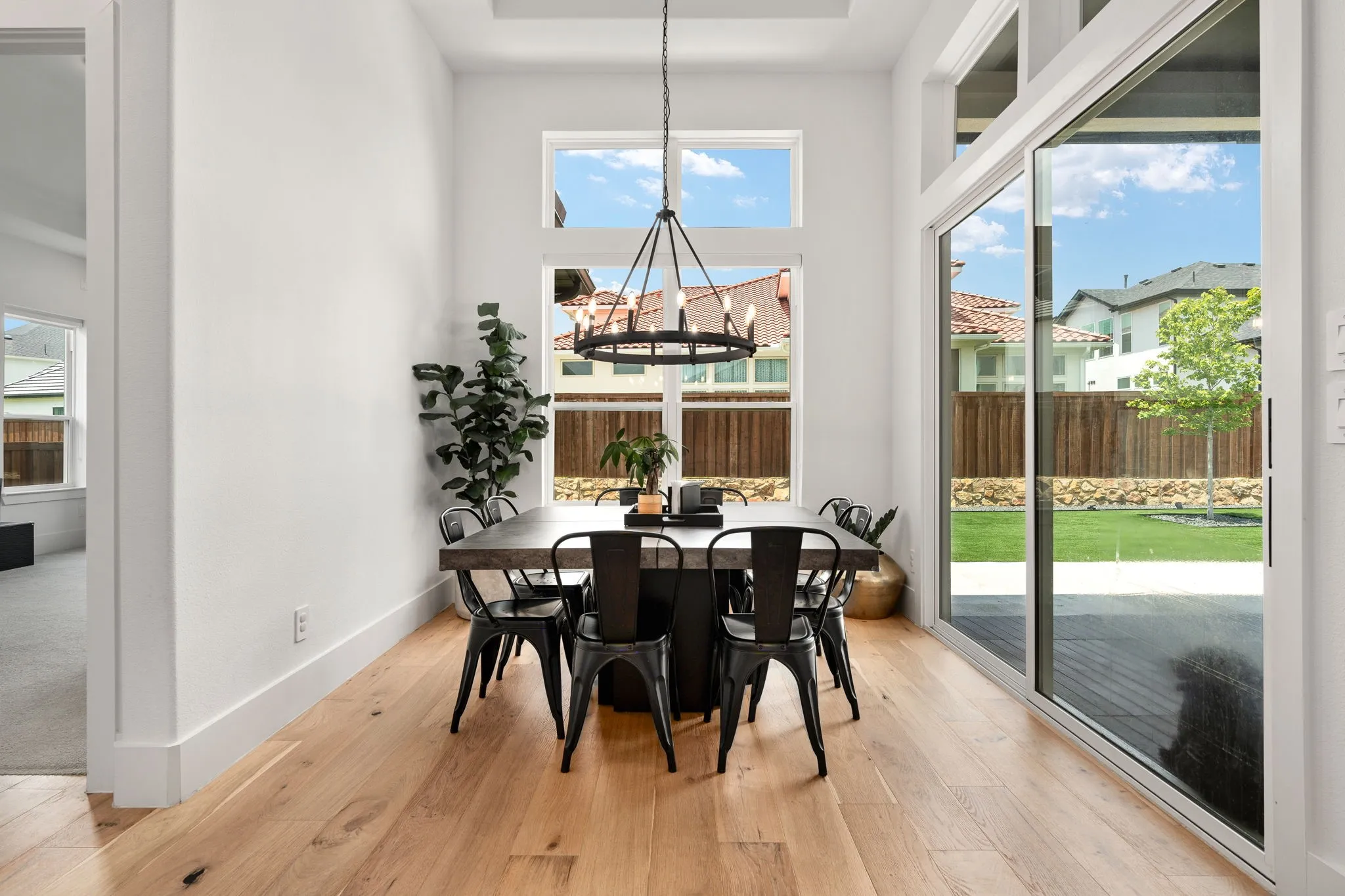 Dining area featuring high ceilings with a tray detail, wood-finish flooring, and a large sliding glass door
