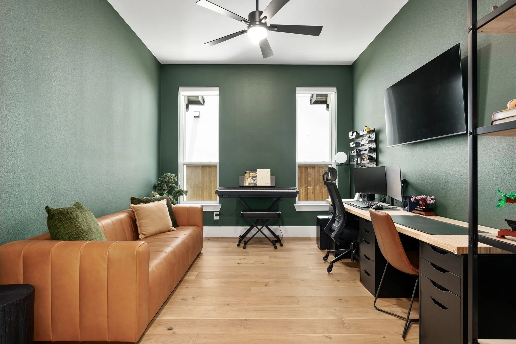 Room featuring light wood-finish flooring, two rectangular windows with white trim, and a ceiling fan with integrated lighting