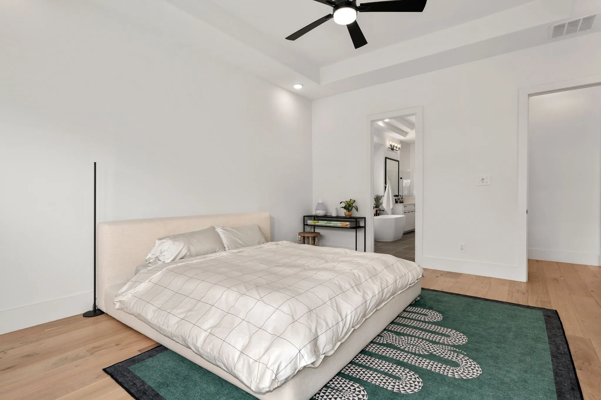 Bright room featuring wood-finish flooring and a tray ceiling with a ceiling fan
