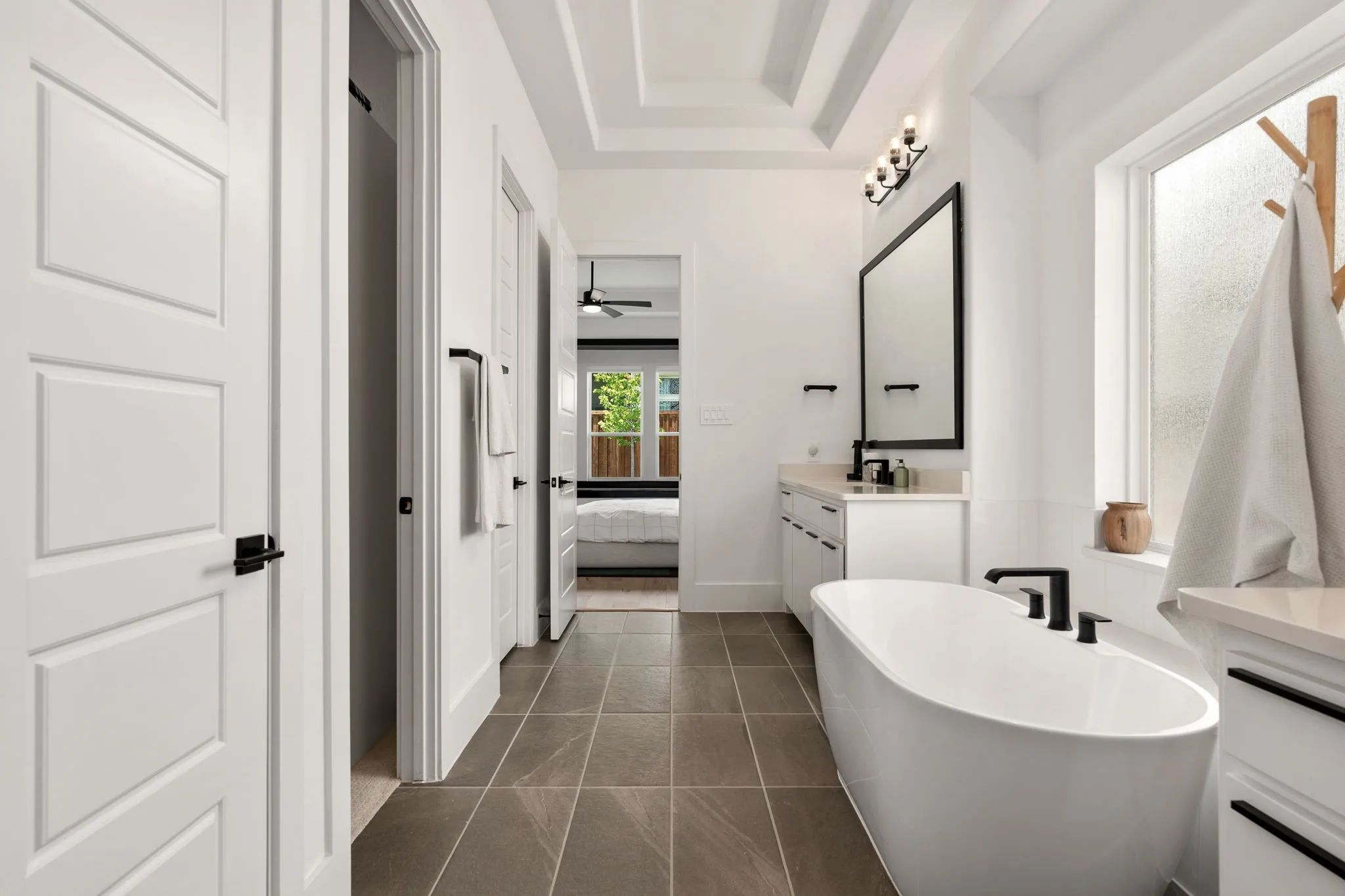 Contemporary bathroom featuring a freestanding tub with matte black fixtures, and a large mirror with a black frame