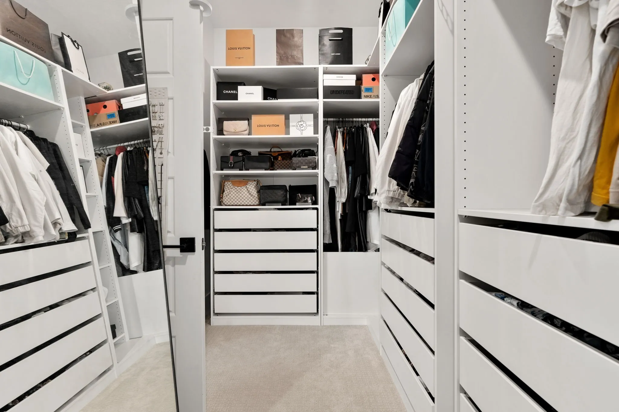Custom closet system featuring multiple hanging rods, integrated shelving, and extensive drawer storage