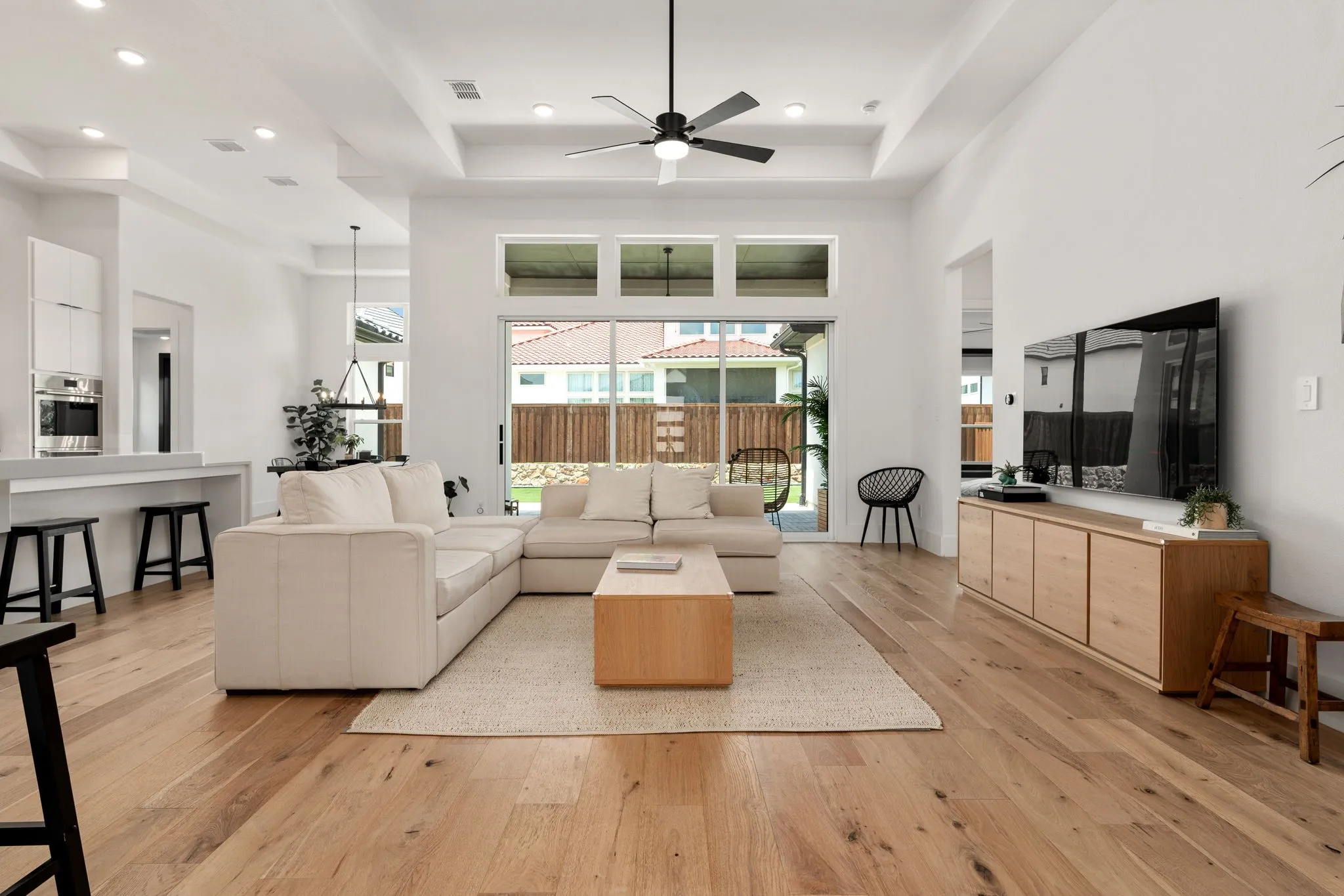Open-concept living area with wood-finish flooring, a tray ceiling, and recessed lighting