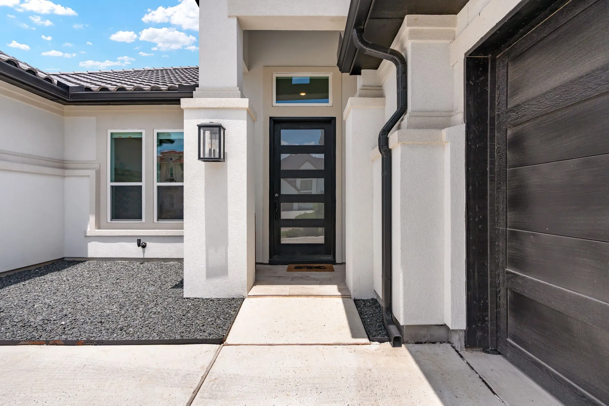Modern entry featuring a dark wood-finish door with frosted glass panels, and a covered porch