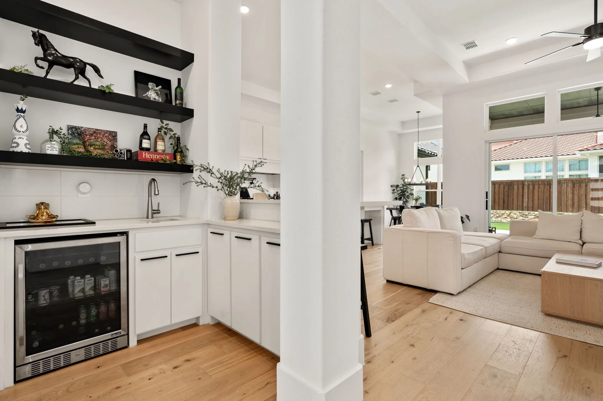 Built-in wet bar featuring a sink, white cabinetry, and open shelving