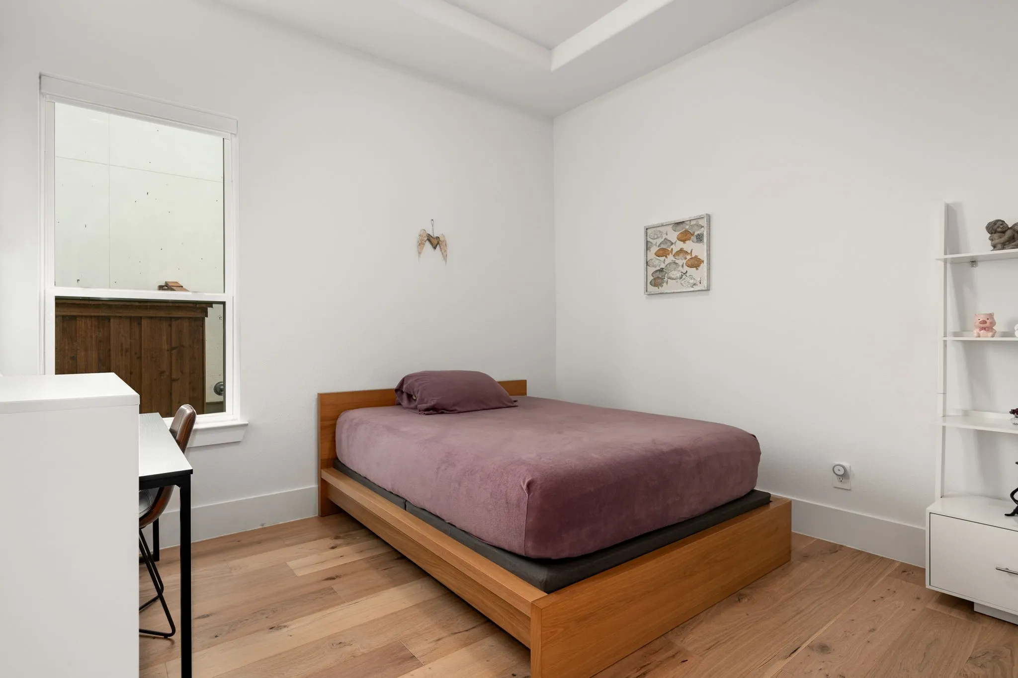 Light-filled room featuring wood-finish flooring, white walls, and a tray ceiling