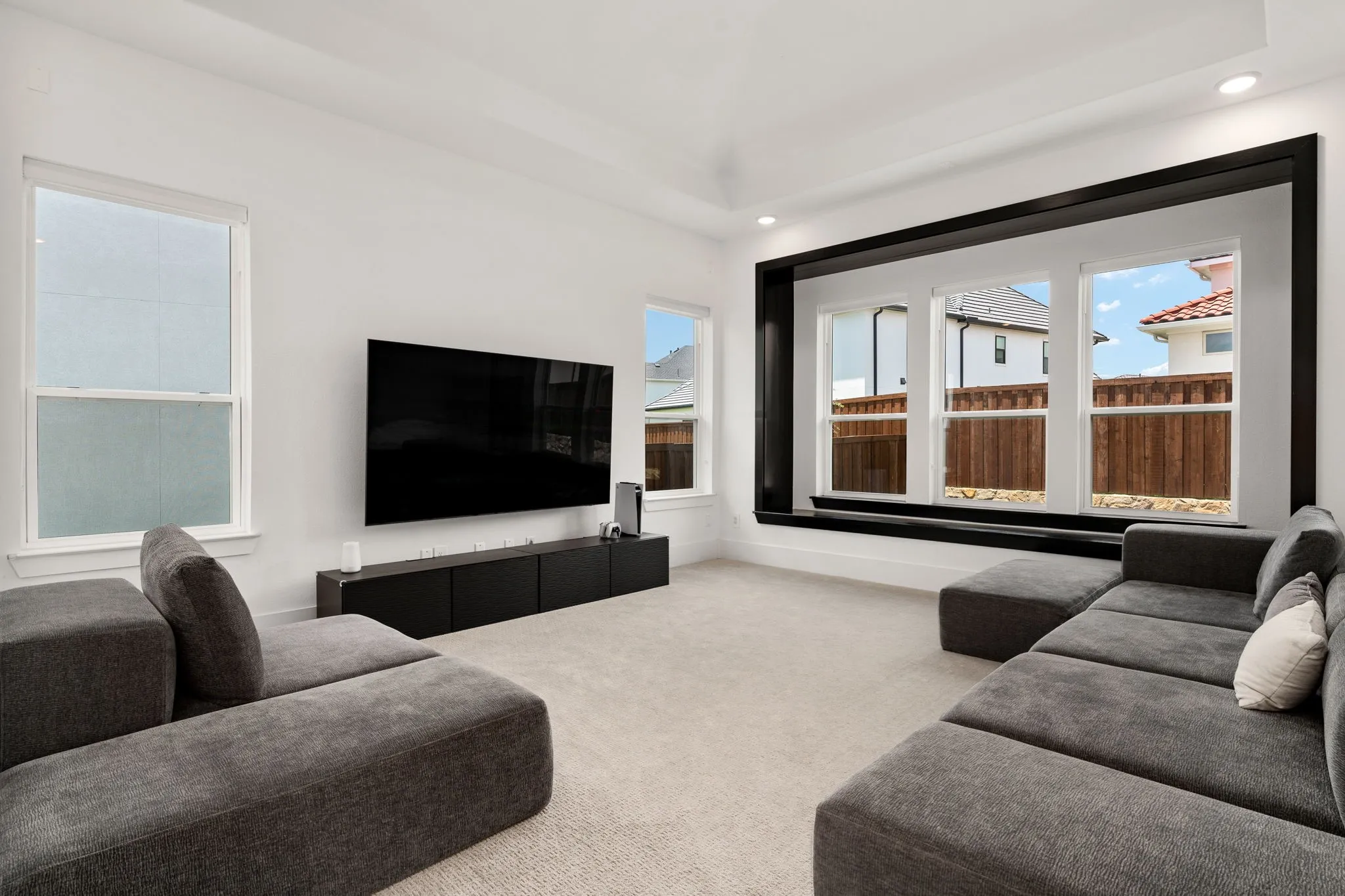 Spacious room featuring a large framed window installation with three vertical windows, recessed lighting, and a tray ceiling