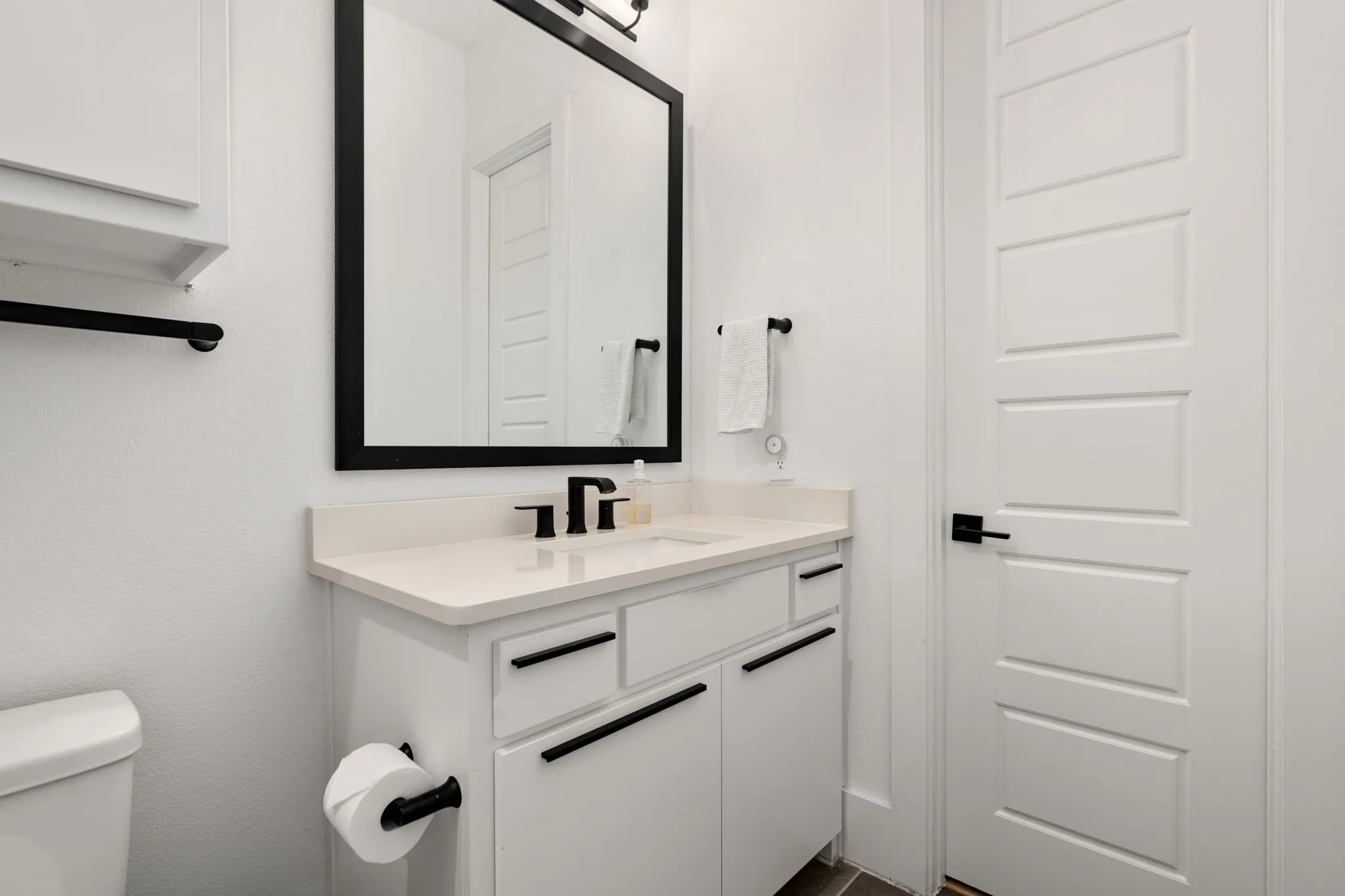 Bathroom vanity featuring a light-toned countertop, integrated sink, and matte black faucet