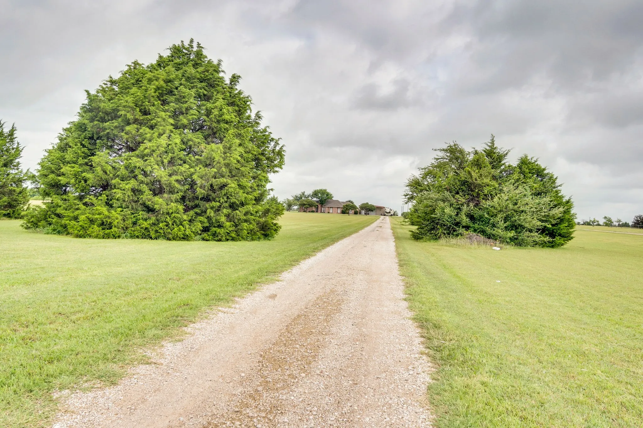 Gravel driveway with expansive green lawn and mature trees