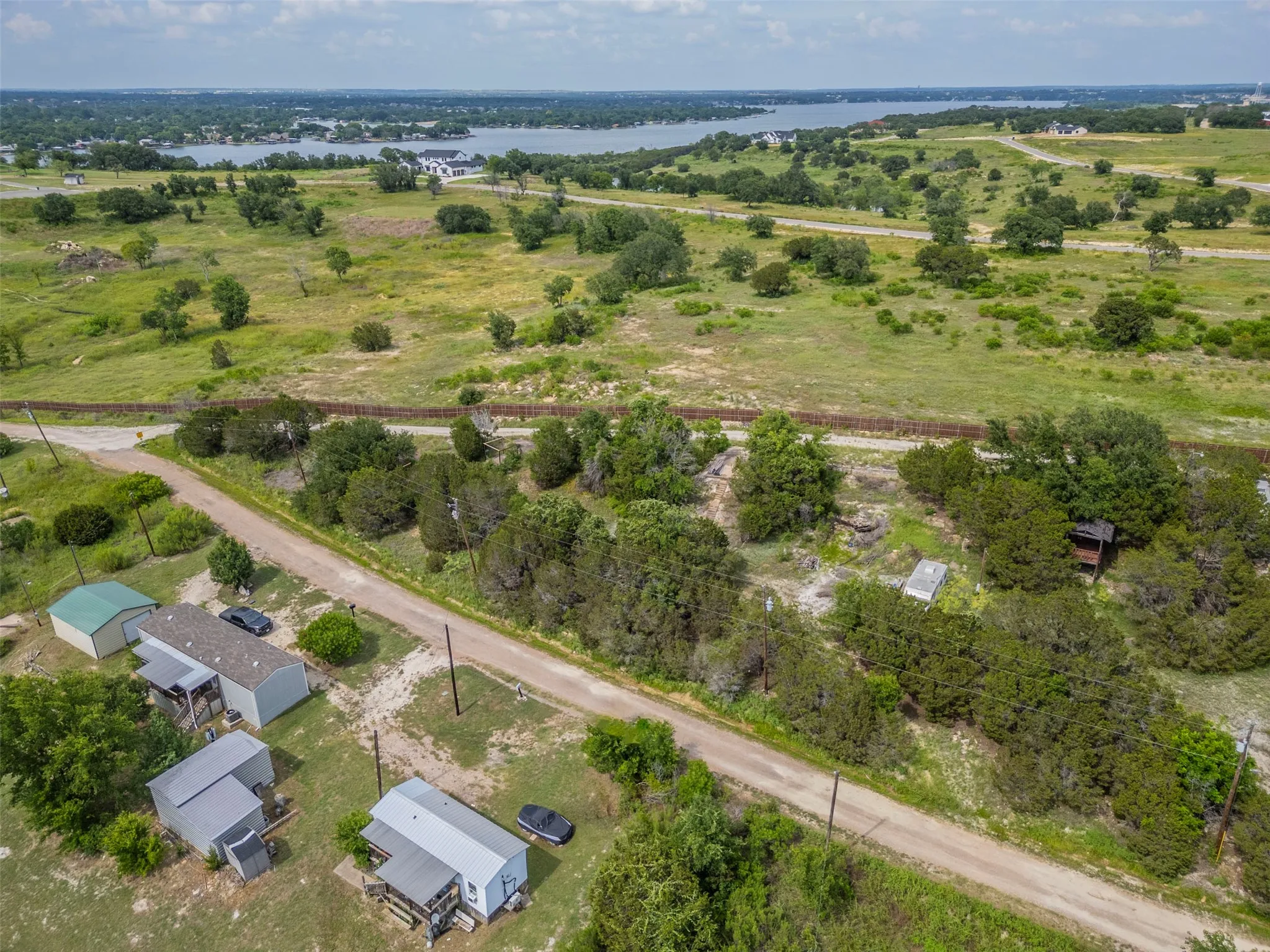 Aerial perspective of a sprawling undeveloped landscape featuring natural terrain, mature trees, and distant water body